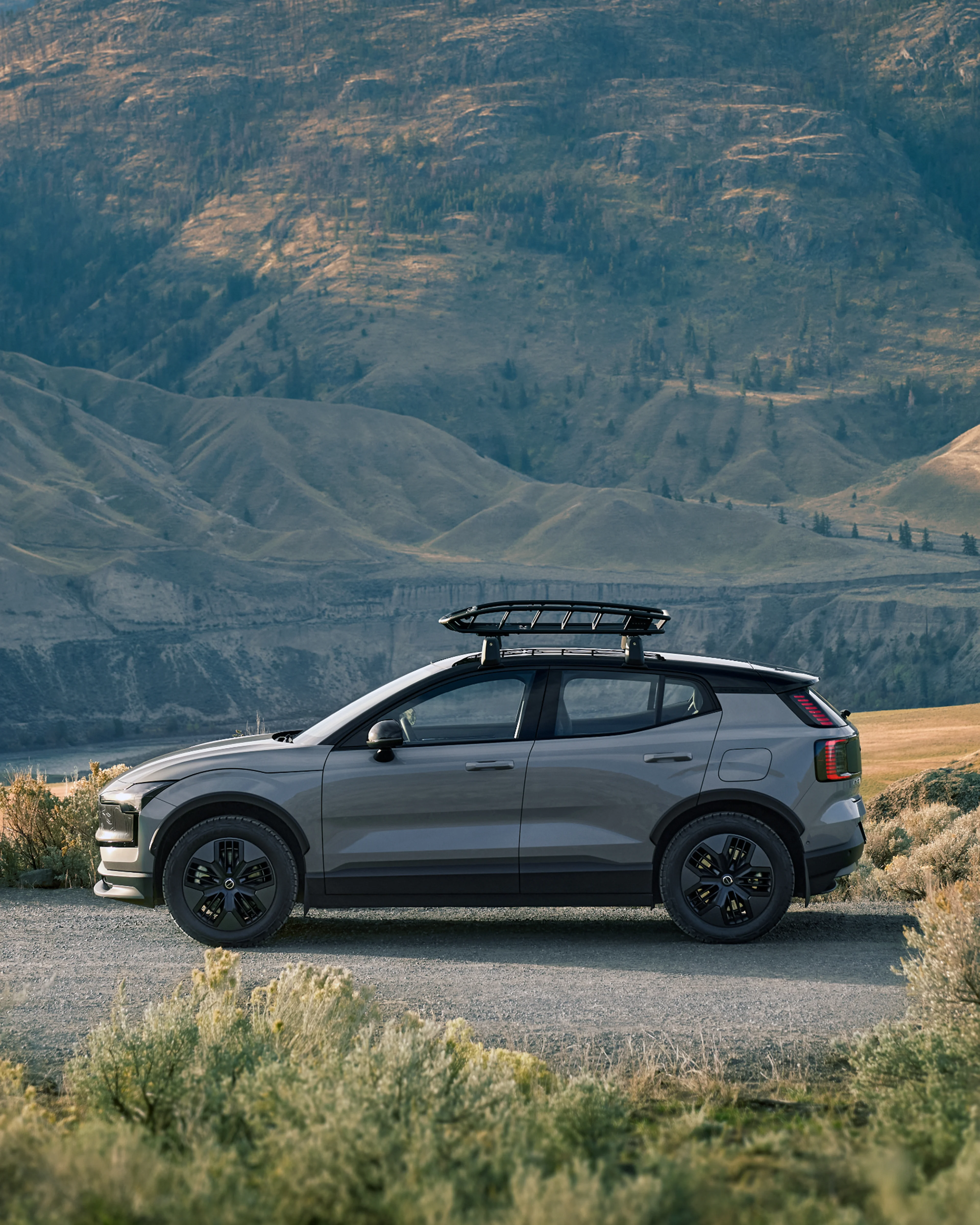 Πλευρική άποψη ενός EX30 Cross Country με σχάρα οροφής σε ημιορεινό σκηνικό.