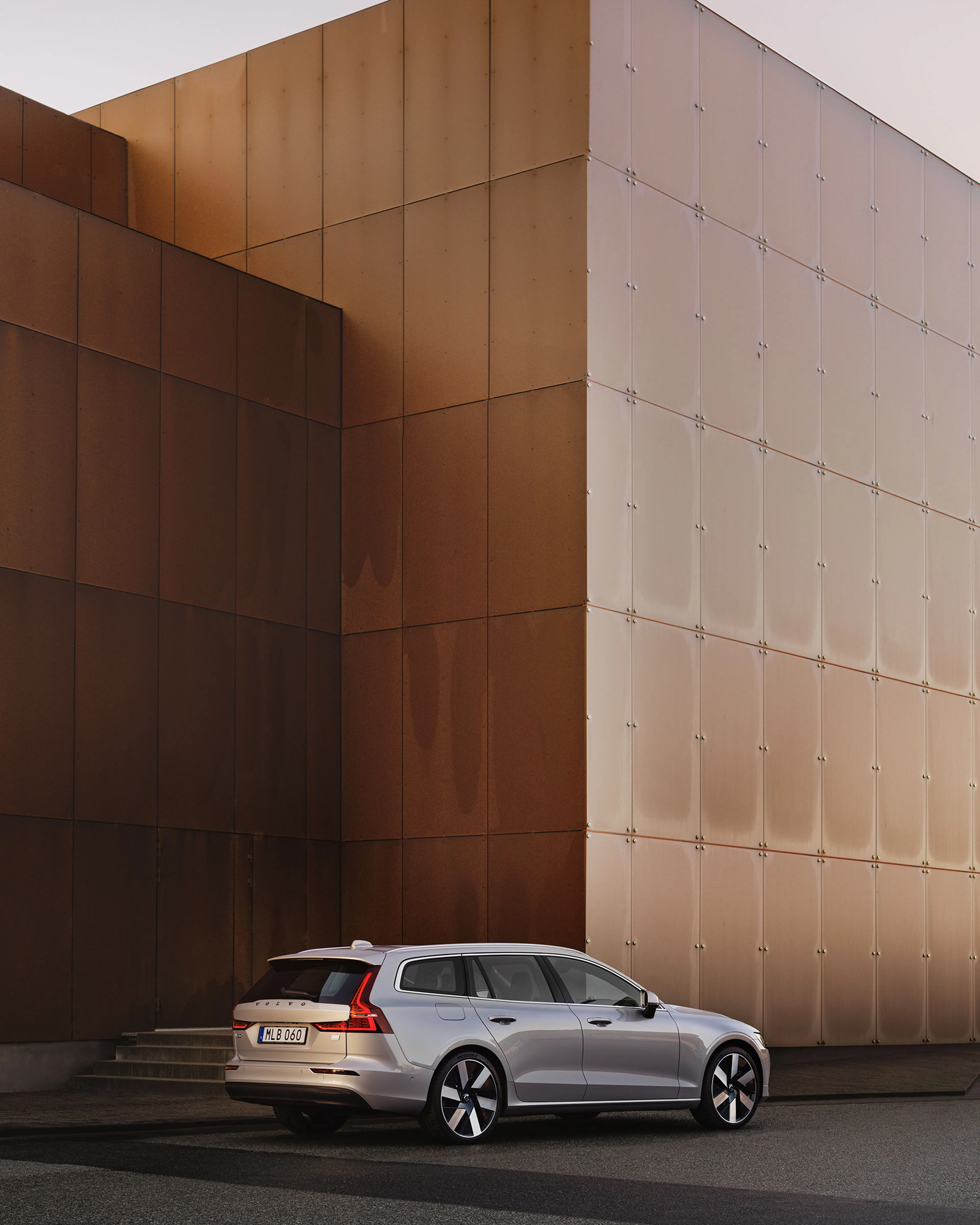 Ein silberner Volvo V60 vor brauner Außenwand, aus der Vogelperspektive mit Fokus auf das seitliche Heck.
