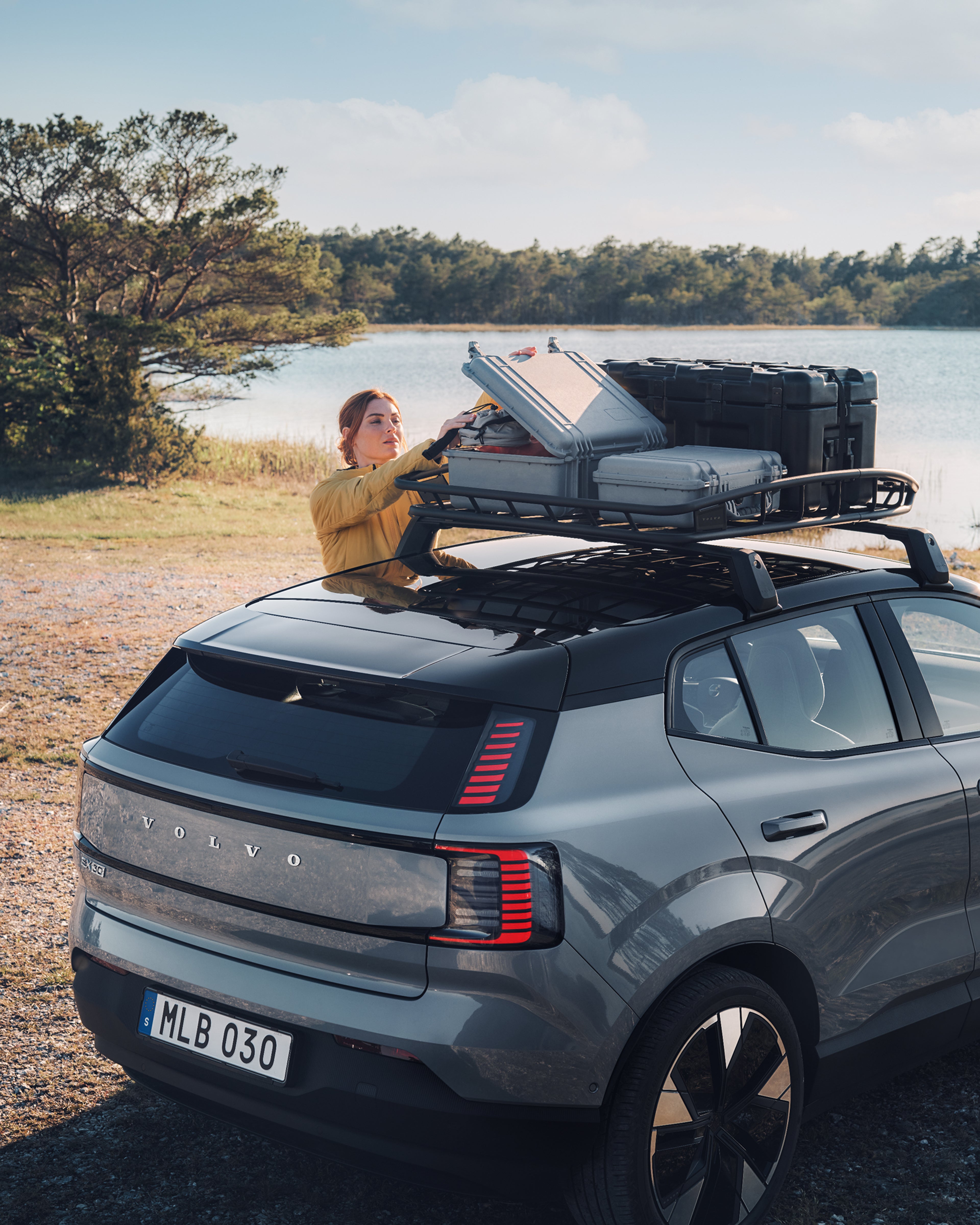 Angled rear view of the EX30, including a woman reaching to the roof basket.
