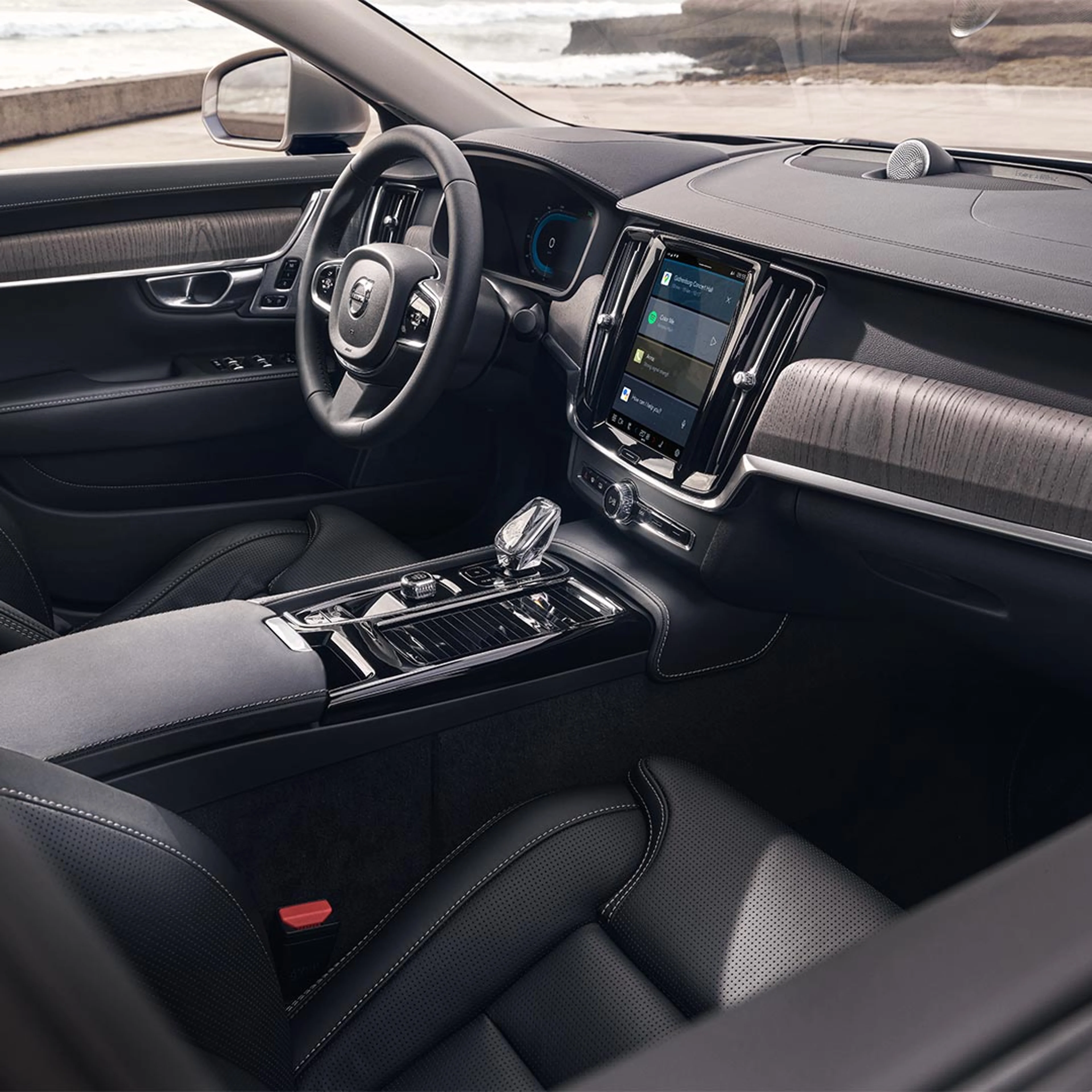 Innenansicht eines Volvo S90 Plug-in Hybrid mit Fahrersitz, Lenkrads und zentralem Touchscreen-Display.