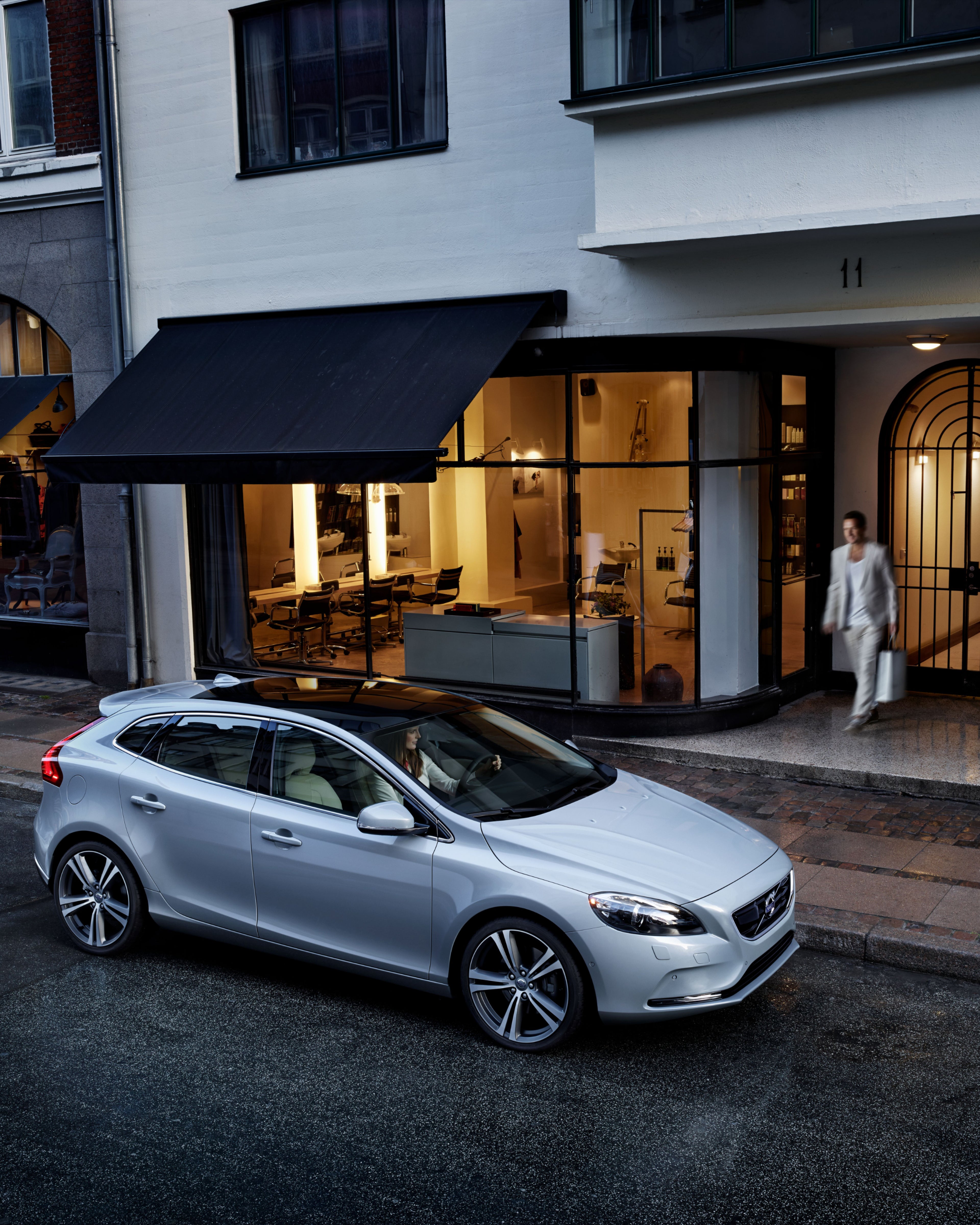 Immagine del lato di una Volvo V40 parcheggiata davanti a un negozio.