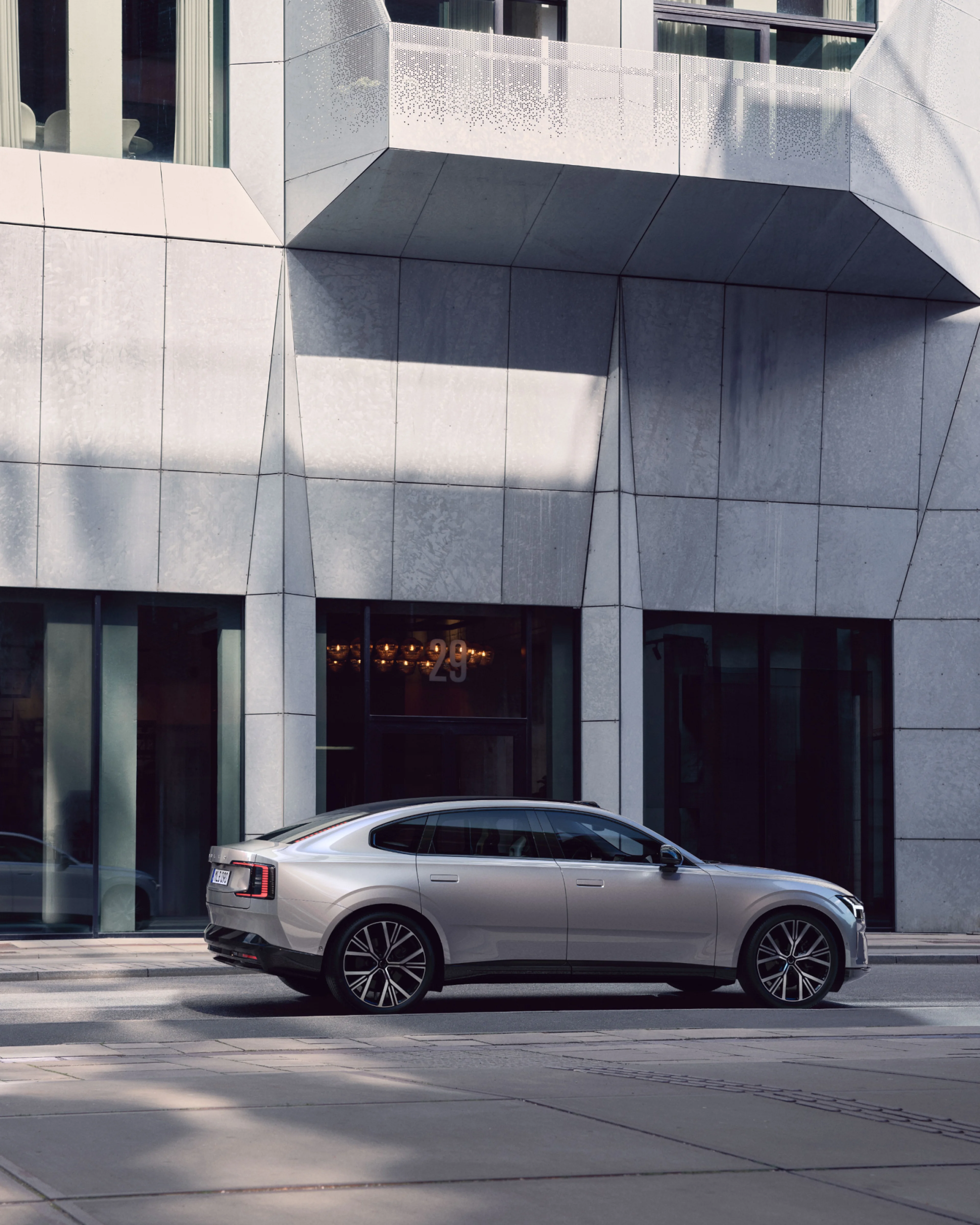 Vista lateral del Volvo ES90 eléctrico frente a un edificio moderno.