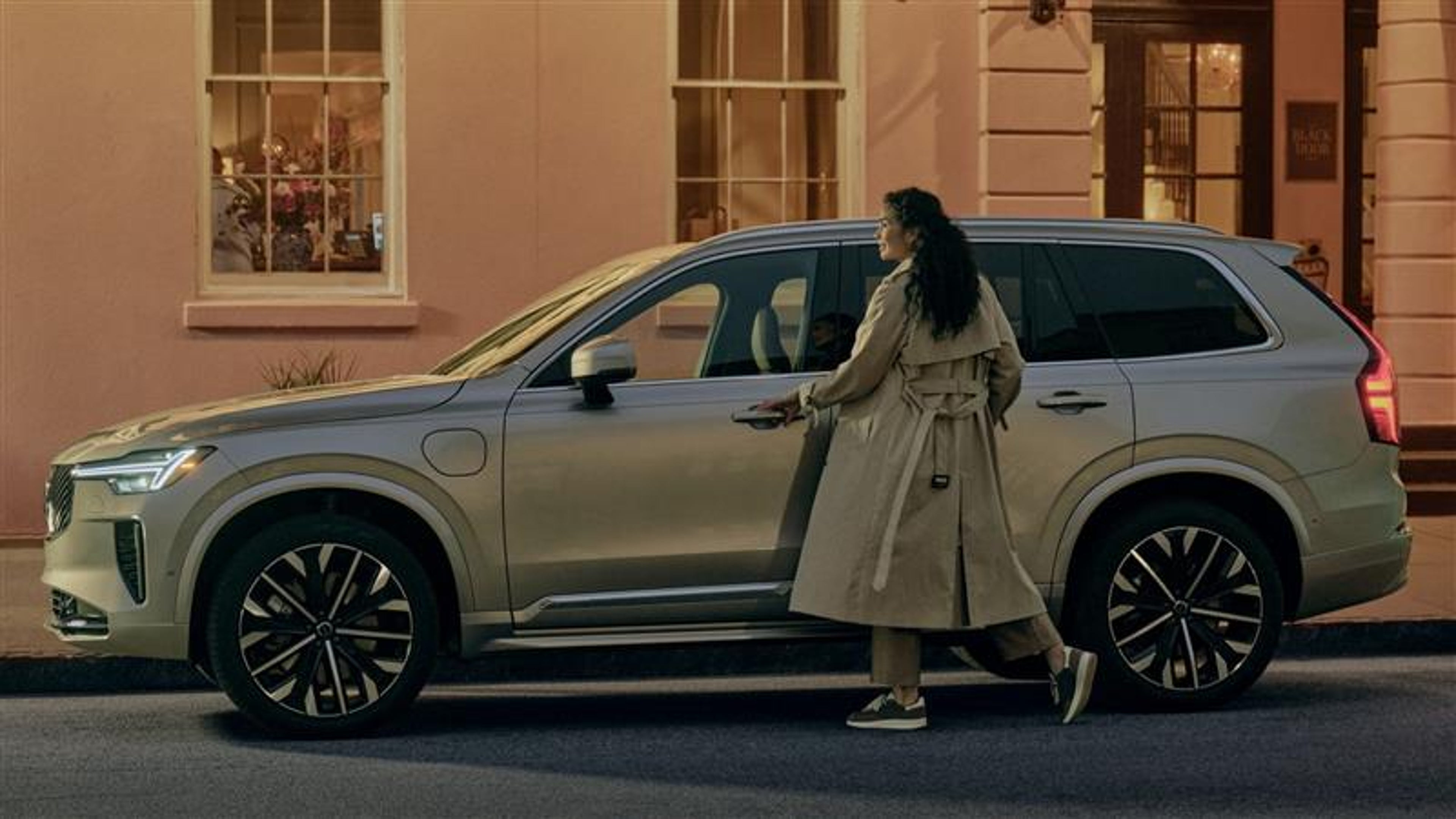 Woman approaching XC90 plug-in hybrid in the evening