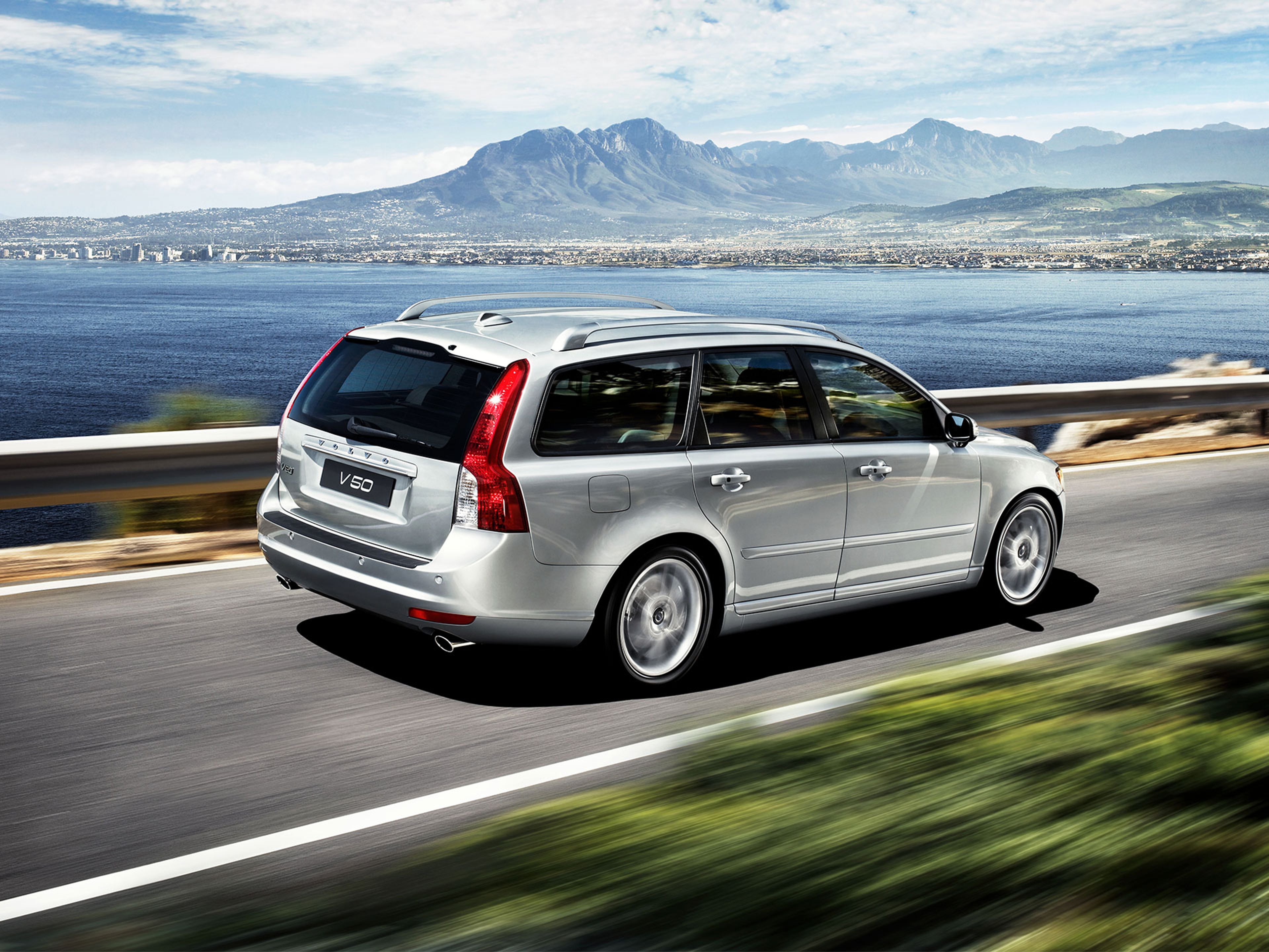 Volvo V50 gris vu de ¾ arrière sur une route de bord de mer