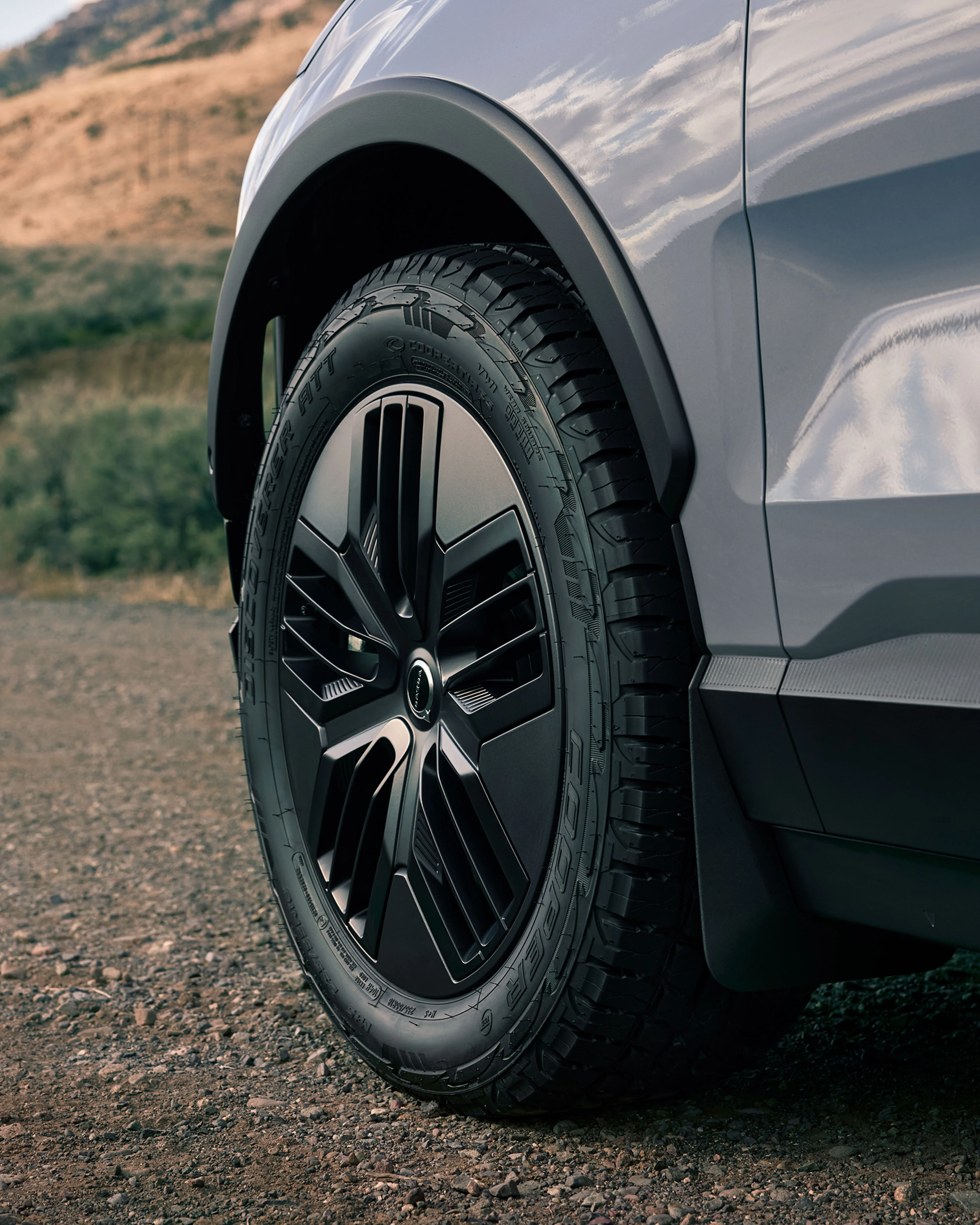 Κοντινή λήψη των τροχών παντός εδάφους του EX30 Cross Country σε έναν δρόμο.