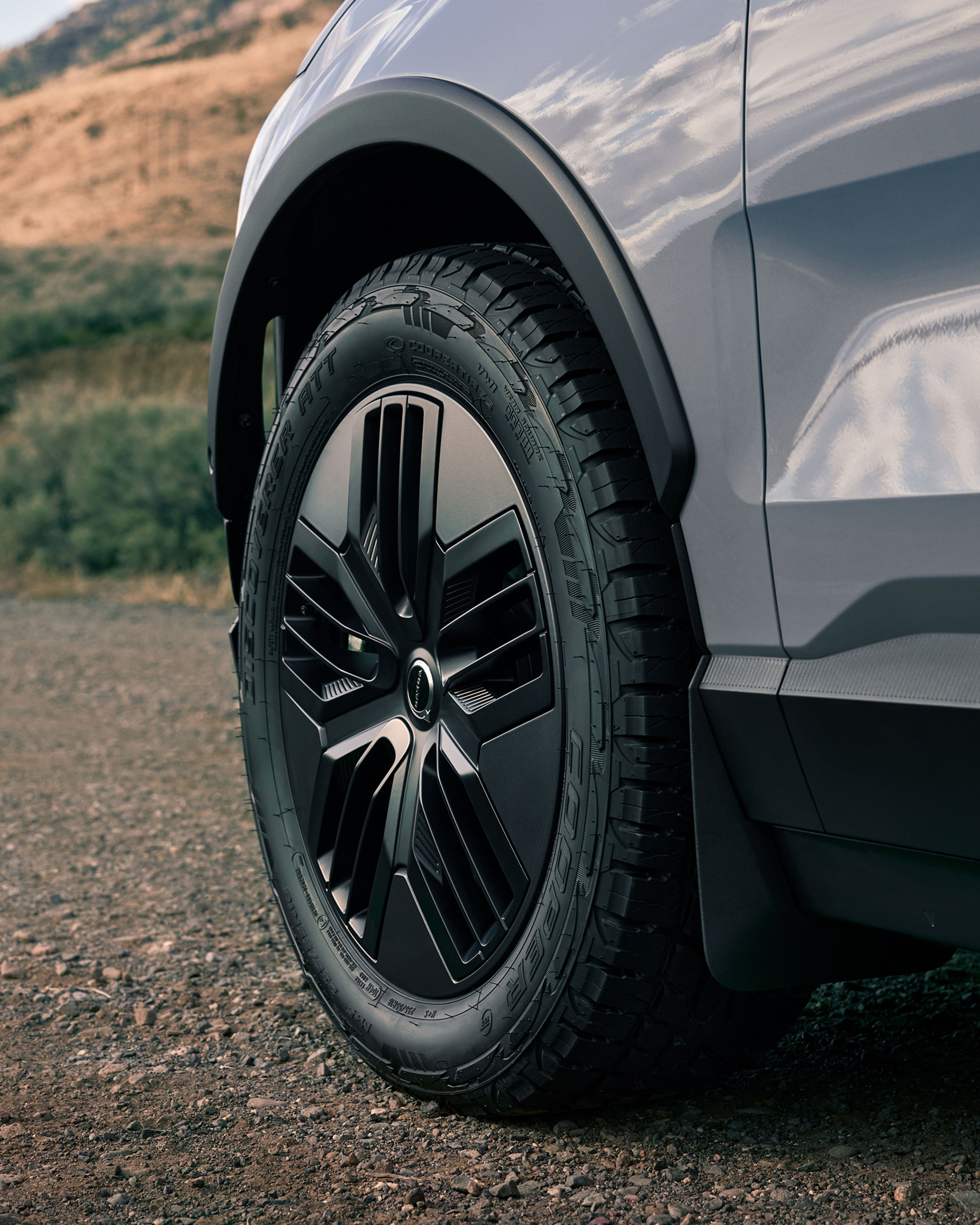 Primeiro plano das rodas all-terrain no EX30 Cross Country na estrada.