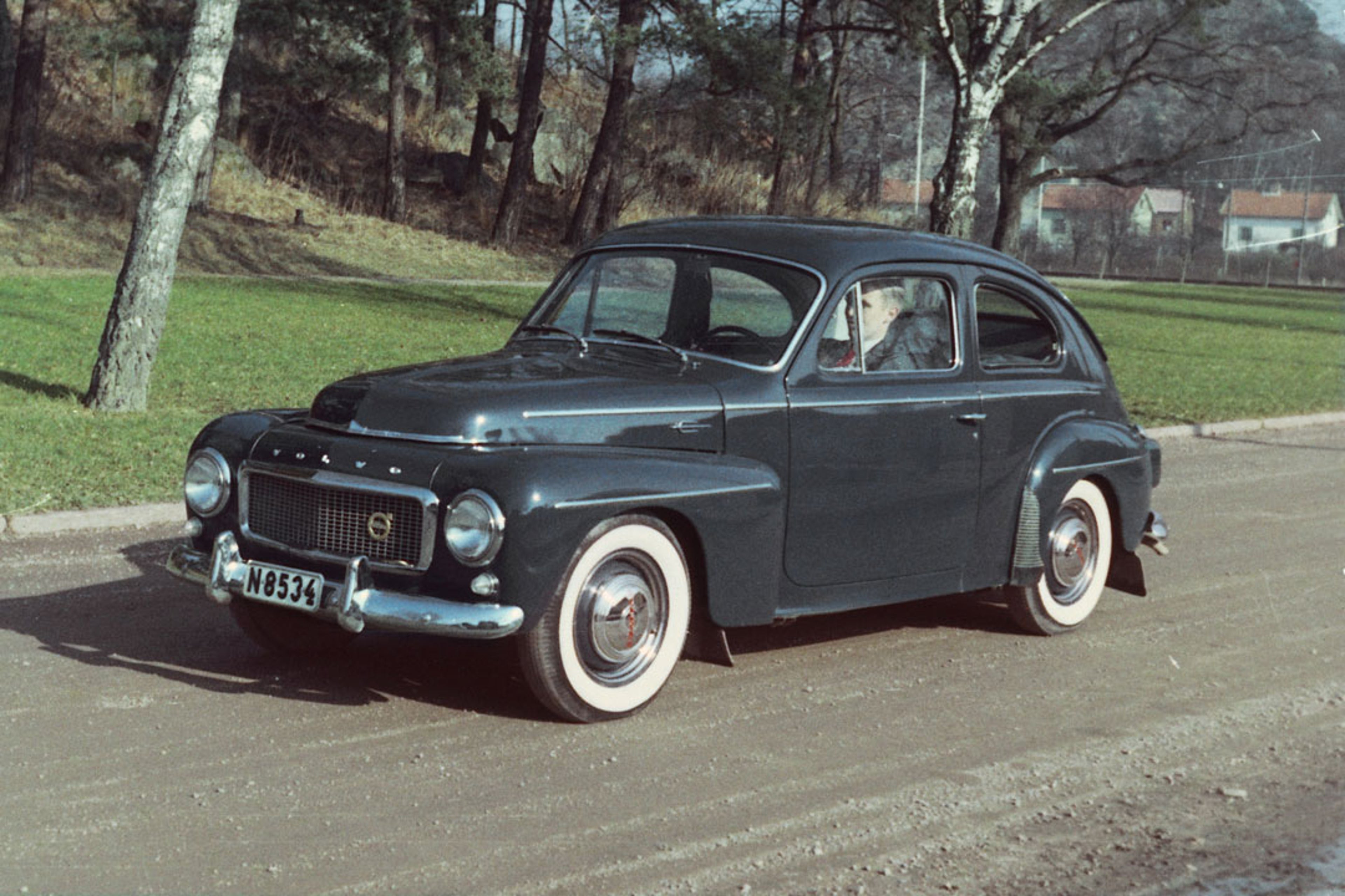 Una fotografía que muestra un Volvo PV544 circulando por una carretera pequeña.