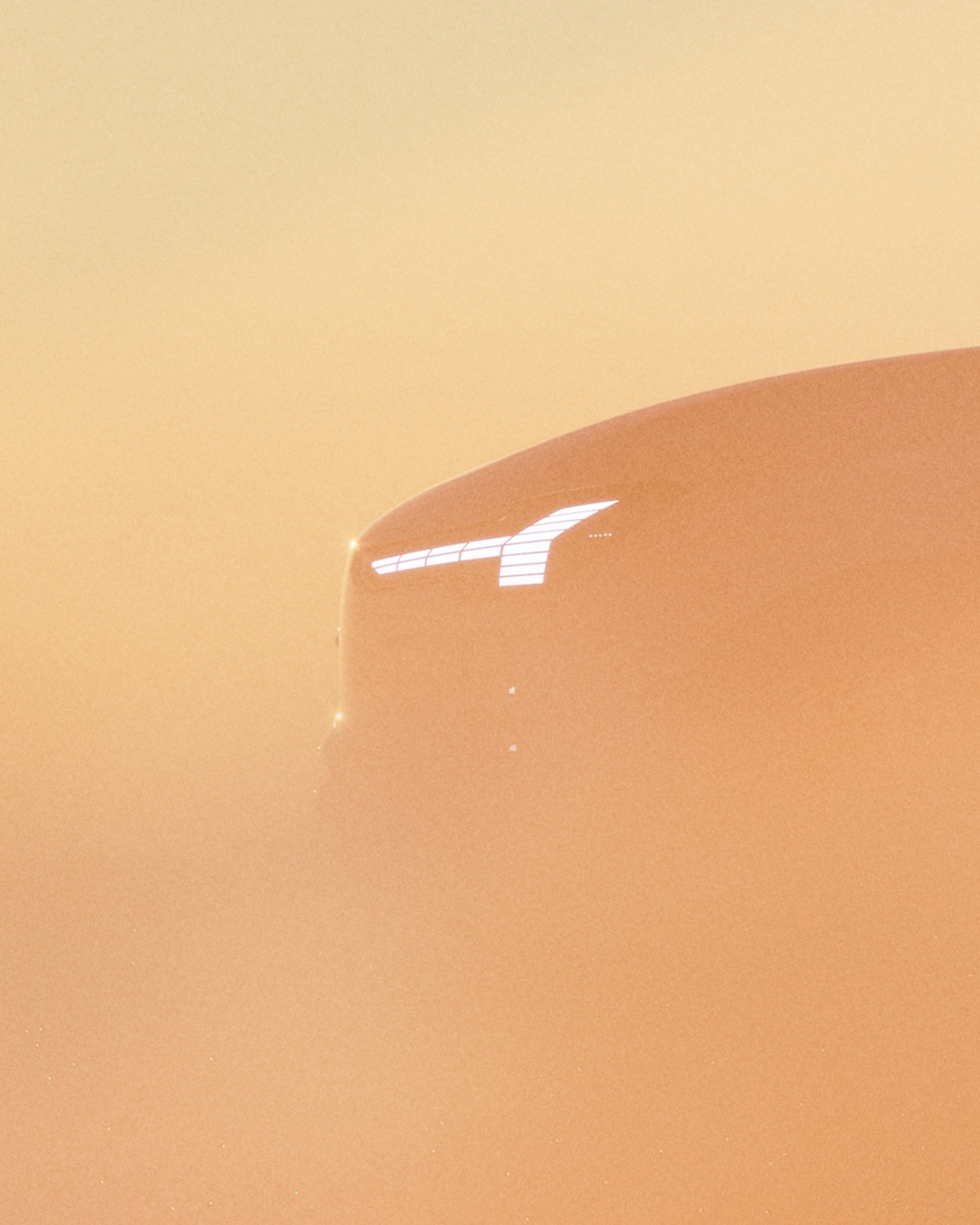 Silueta vozu Volvo EX60 s rozsvícenými světlomety prosvítající skrz oranžovou mlhu.