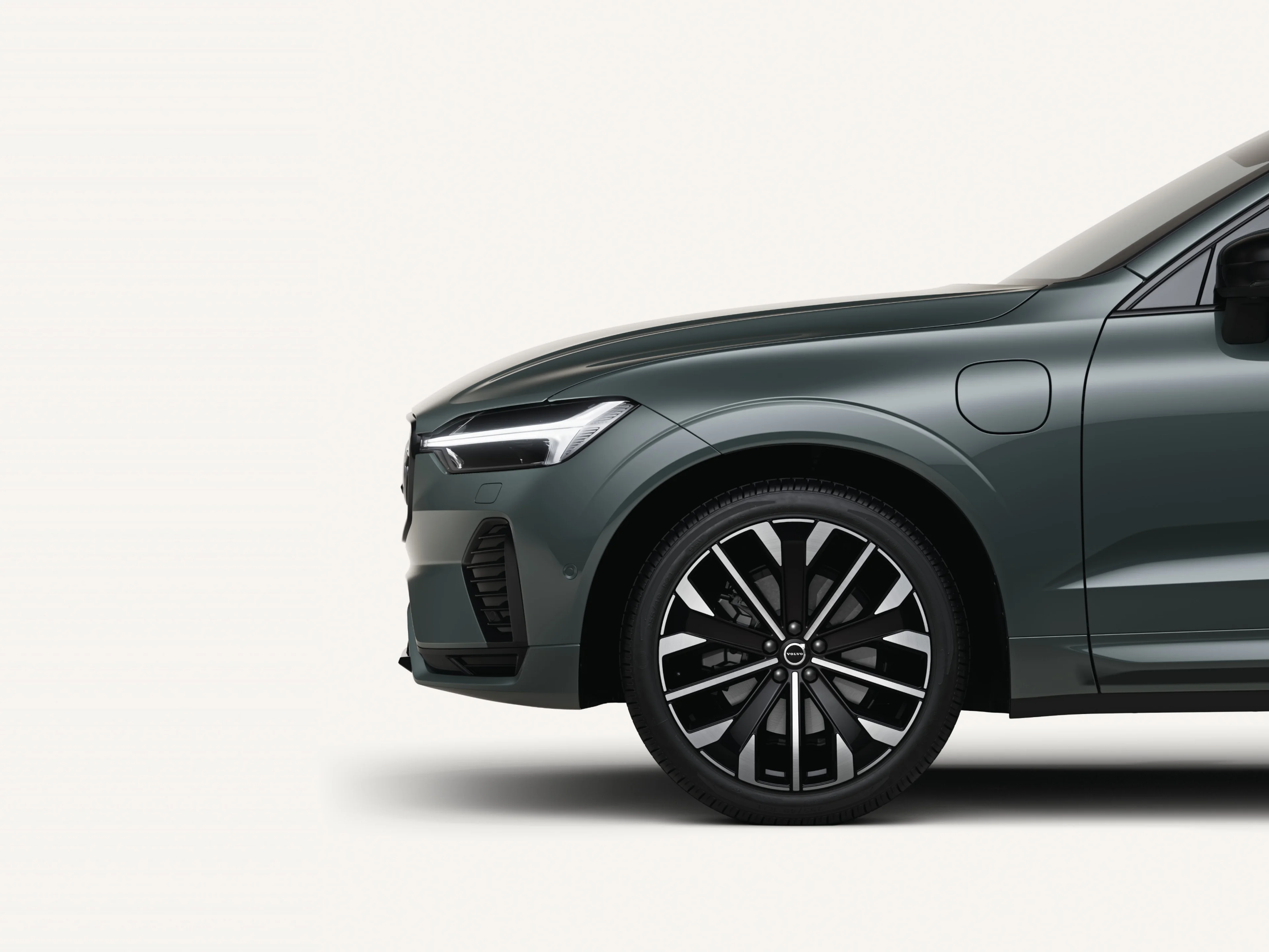 Przednia połowa średniej wielkości SUV-a Volvo XC60 o napędzie hybrydowym typu Plug-in w białym studiu.