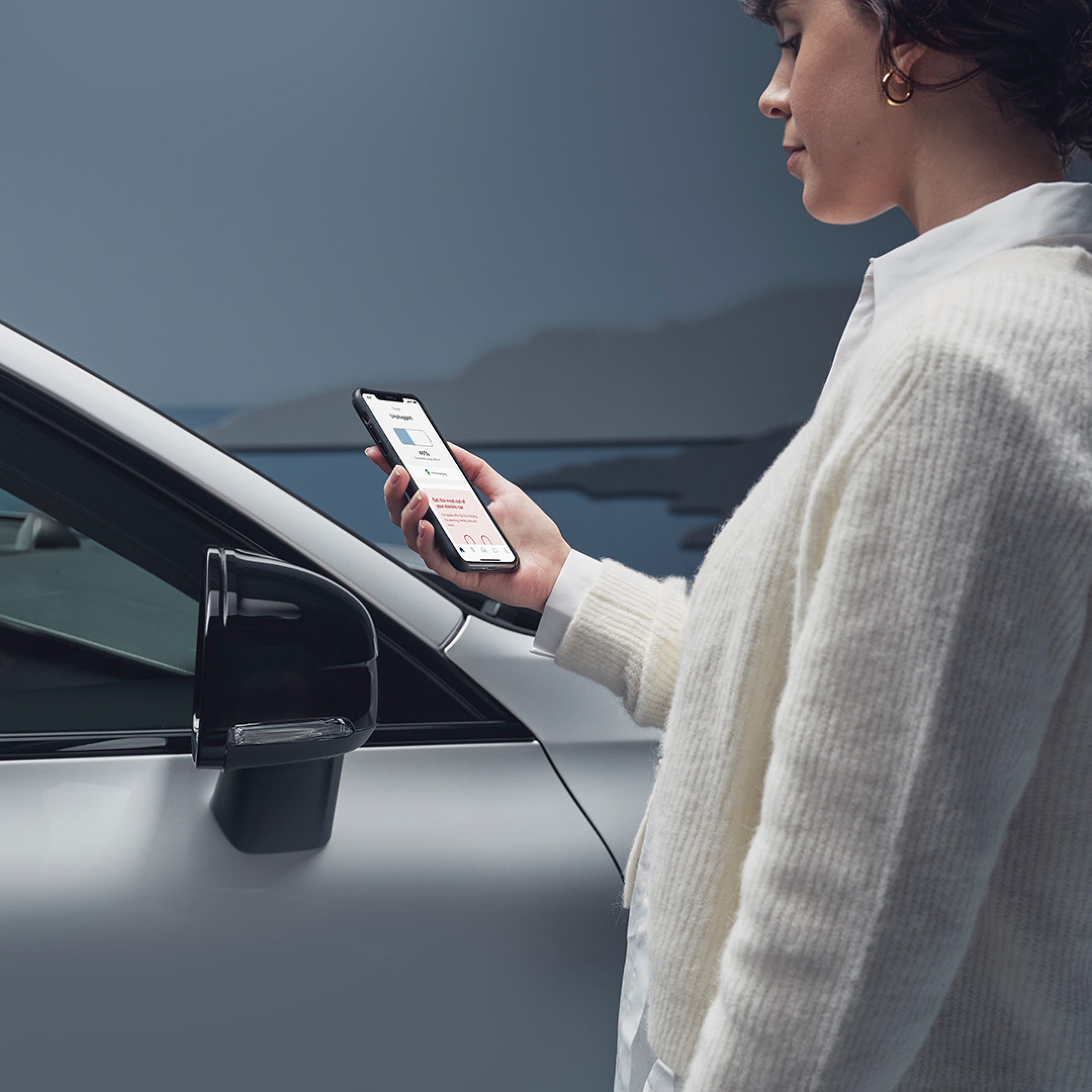 A woman uses her mobile phone to access the Volvo Cars app.