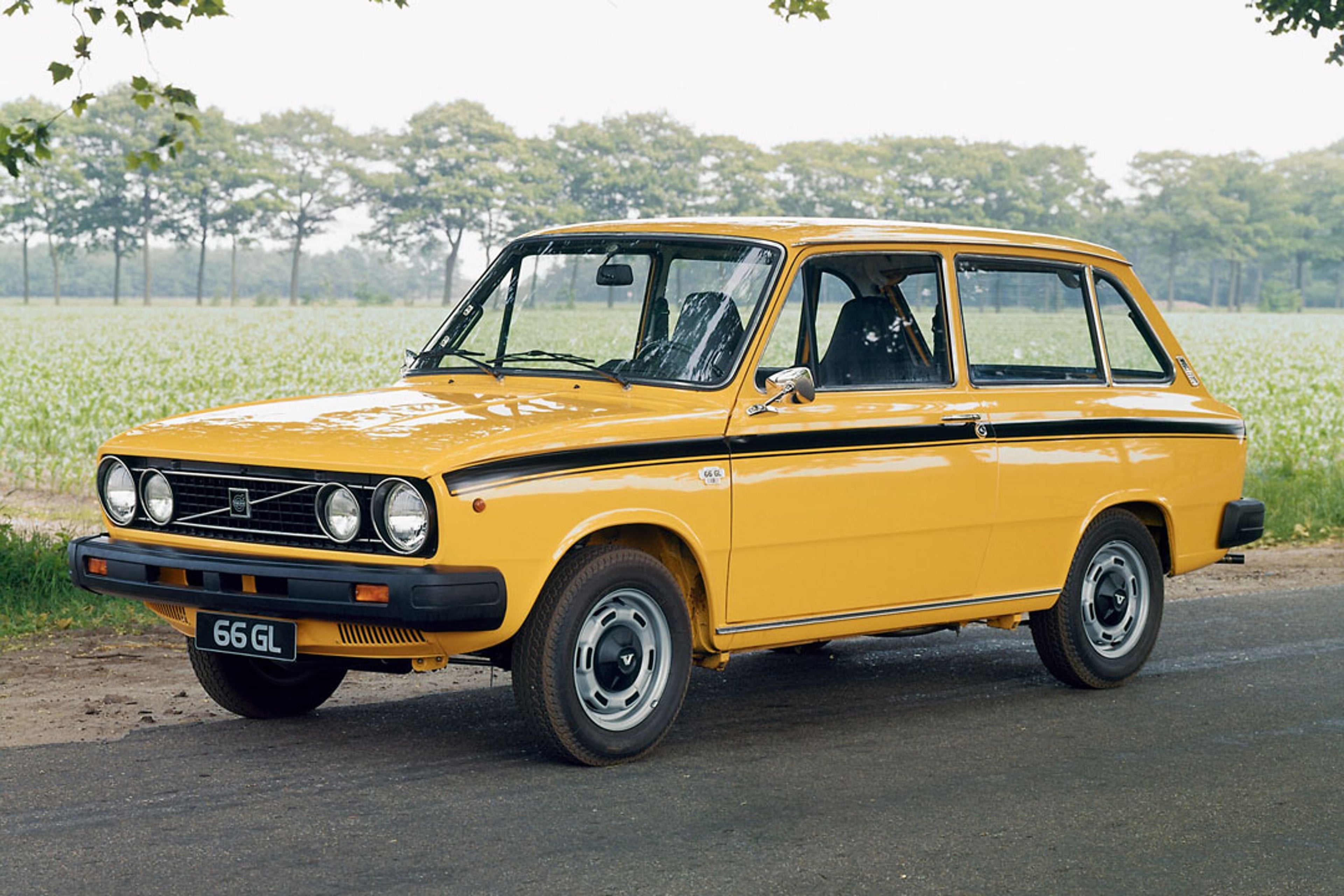 Un Volvo 66 amarillo circulando por una carretera pequeña.