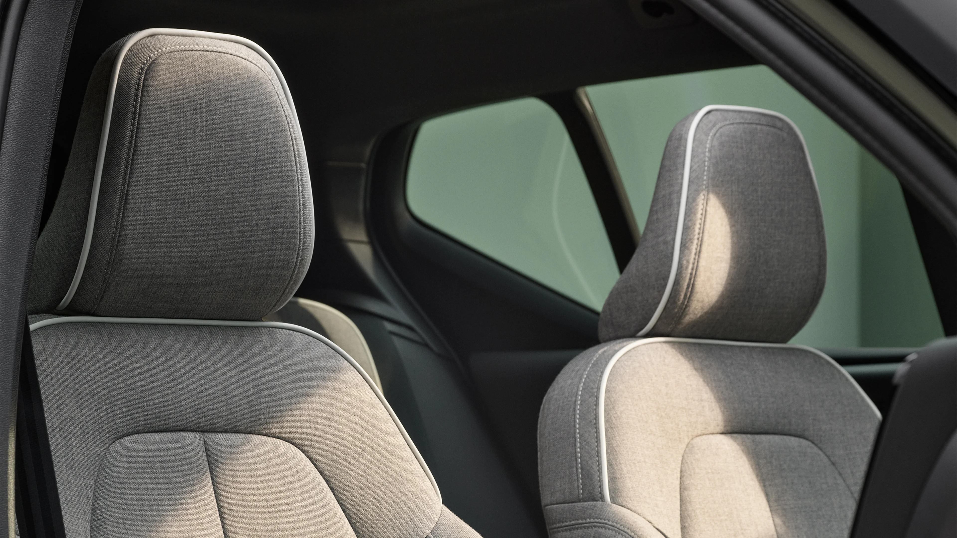 Сидіння переднього пасажира та водія повністю електричного Volvo XC40 Recharge з оббивкою сірого кольору із суміші вовни з білою окантовкою.