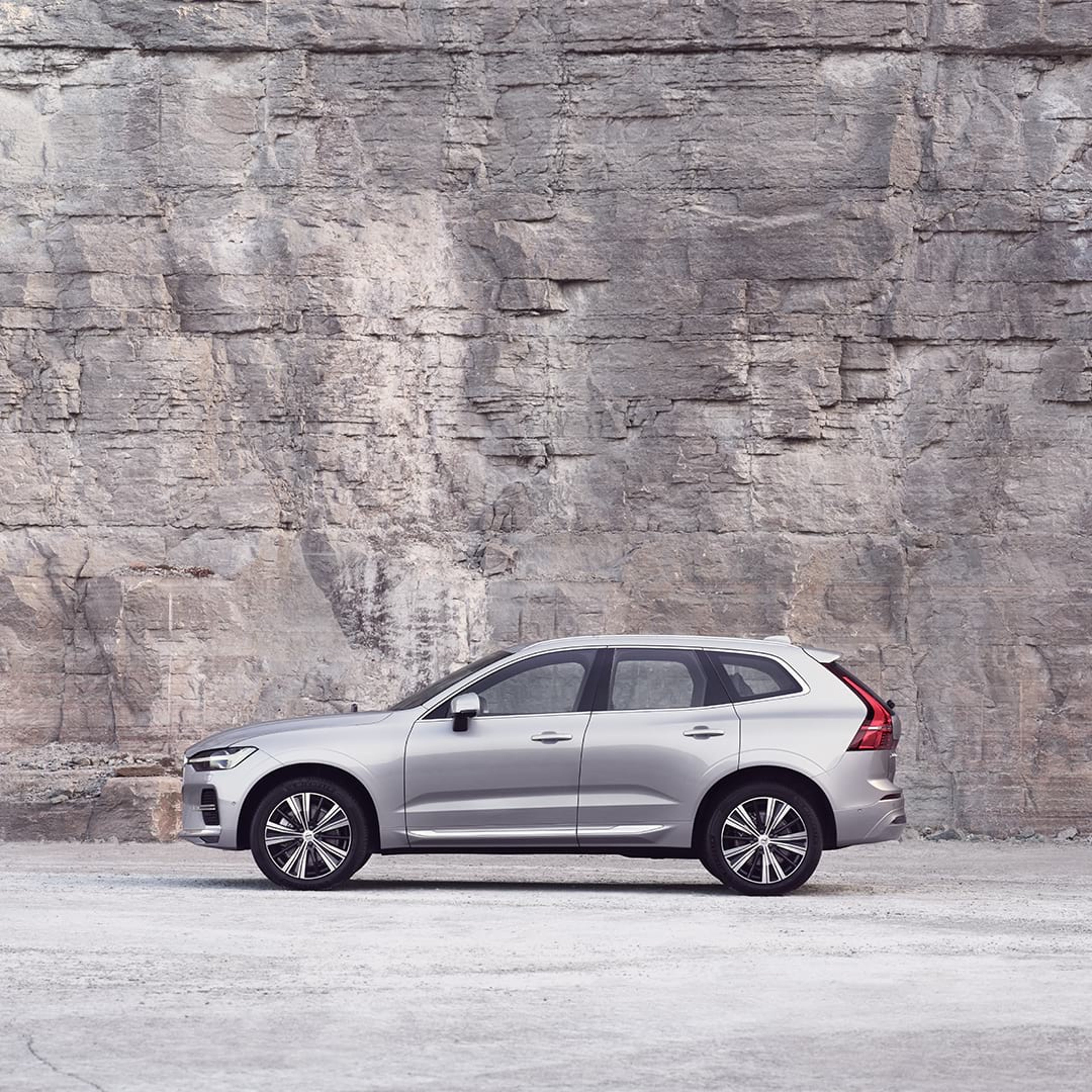 Un Volvo XC60 plateado parado frente a una pared de roca.