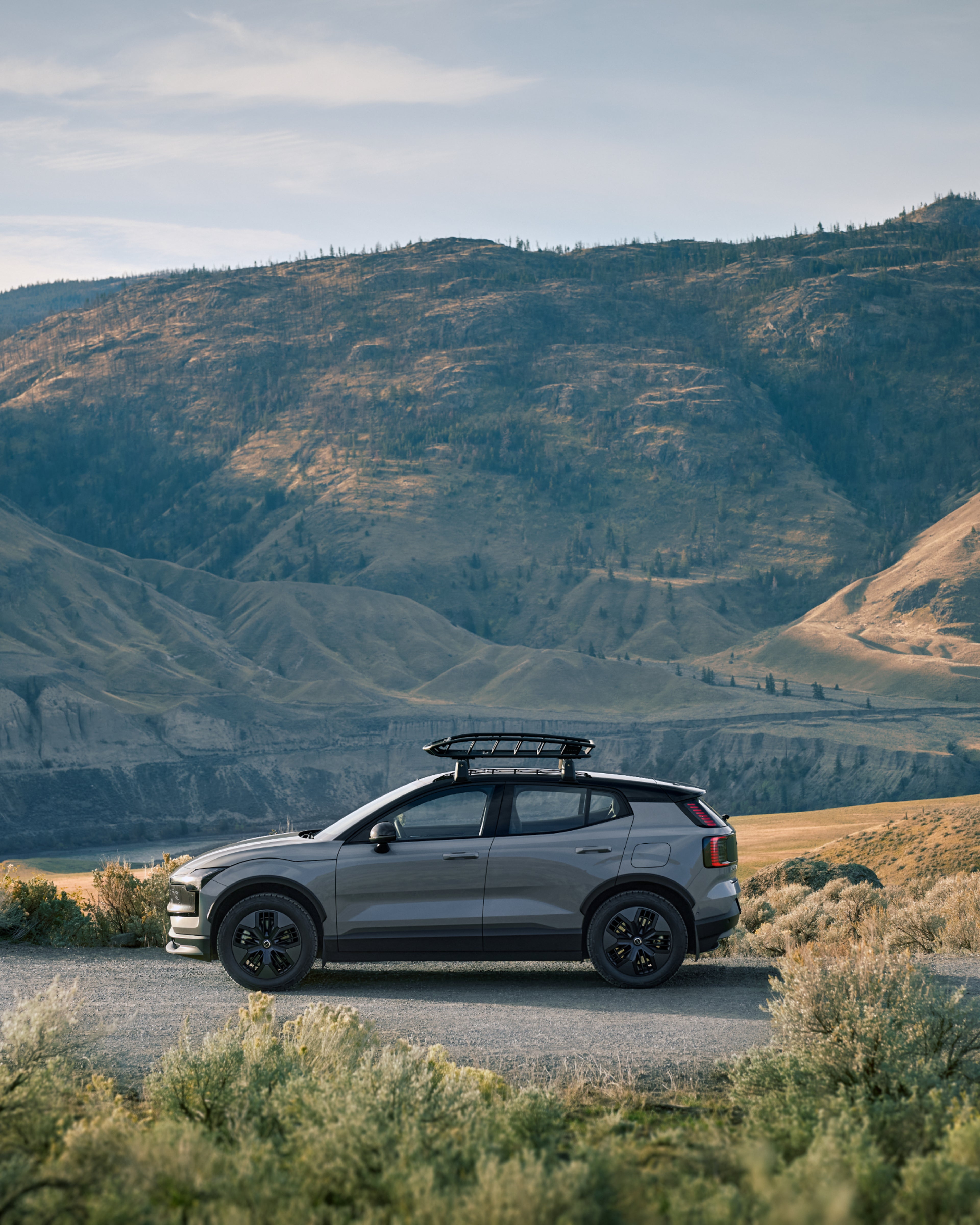 The EX30 Cross Country with a rooftop basket shown from the side in a hilly environment.
