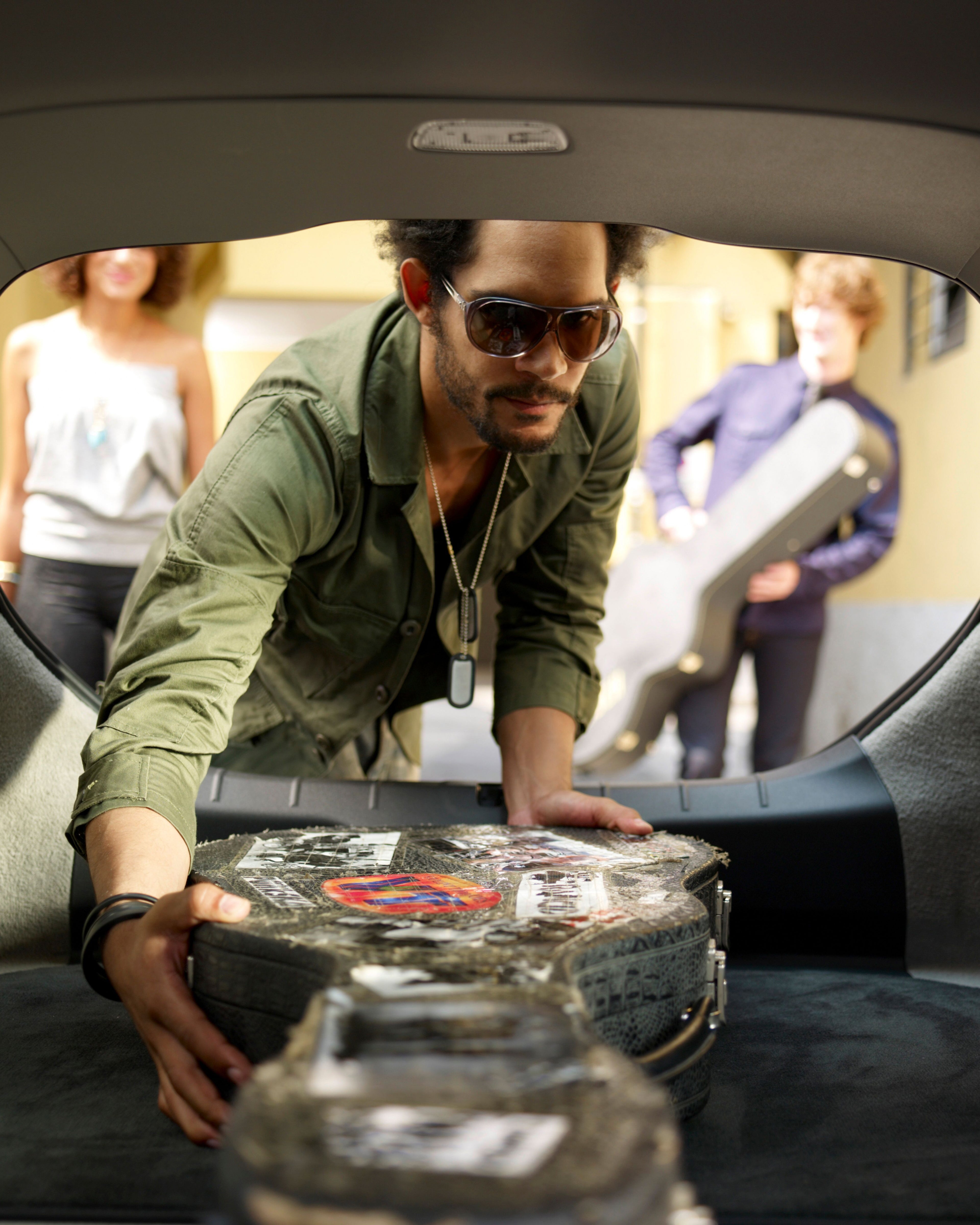 Un hombre cargando una guitarra en el maletero de un Volvo C30.