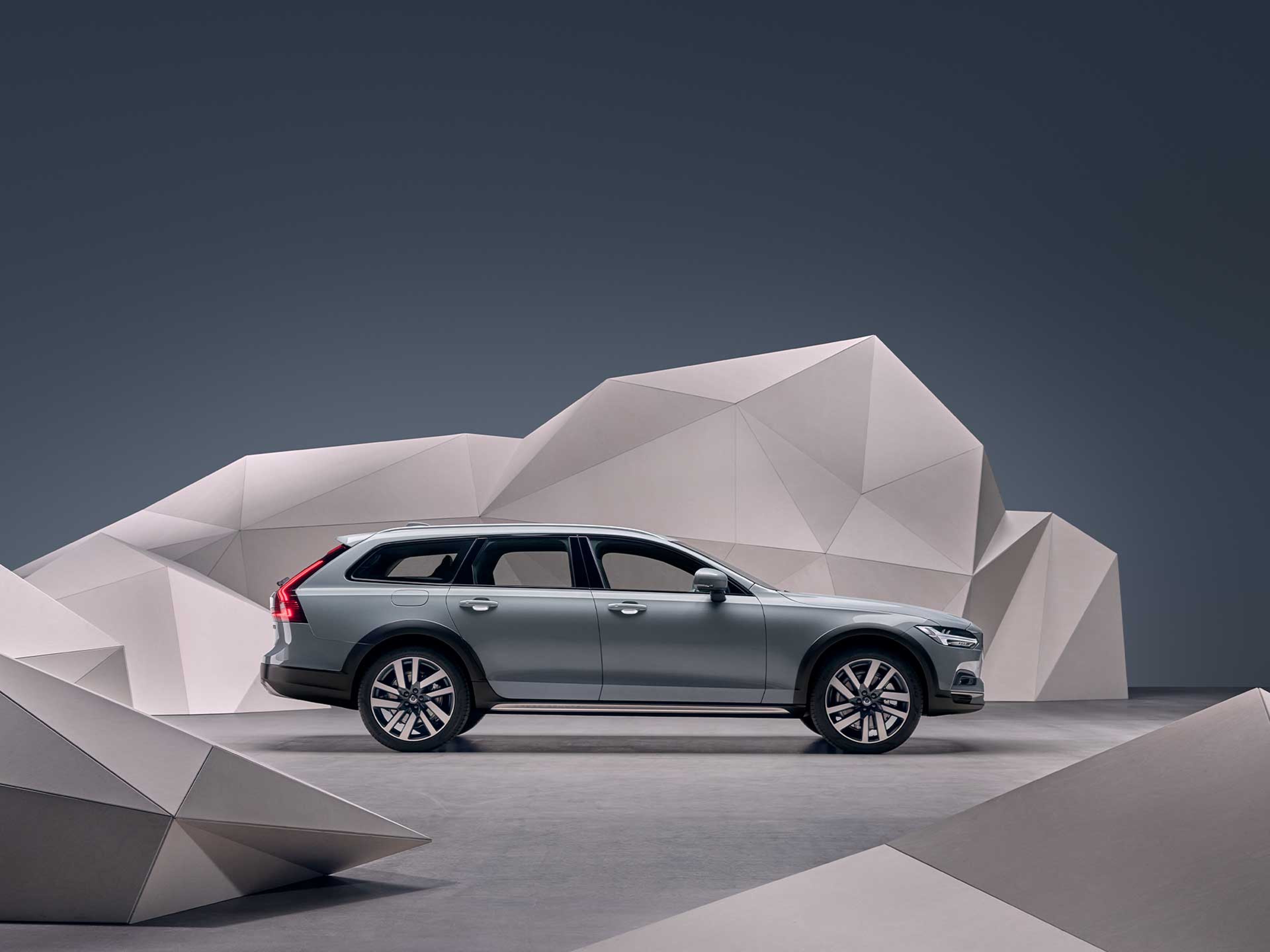 Una Volvo V90 Cross Country grigia di fronte a una parete artistica.