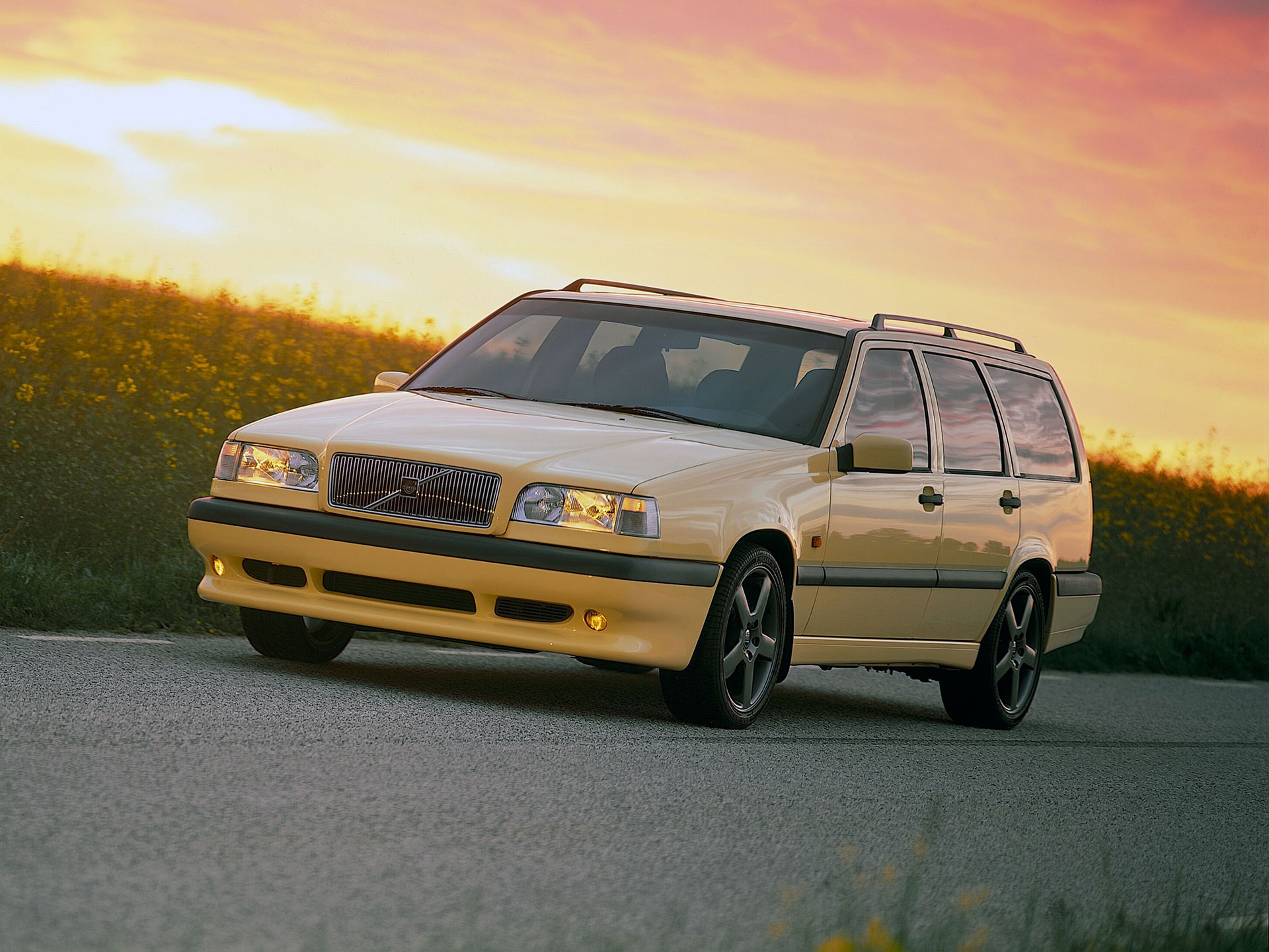 Volvo 850 Break jaune circulant sur une route de campagne le lond d’un champ