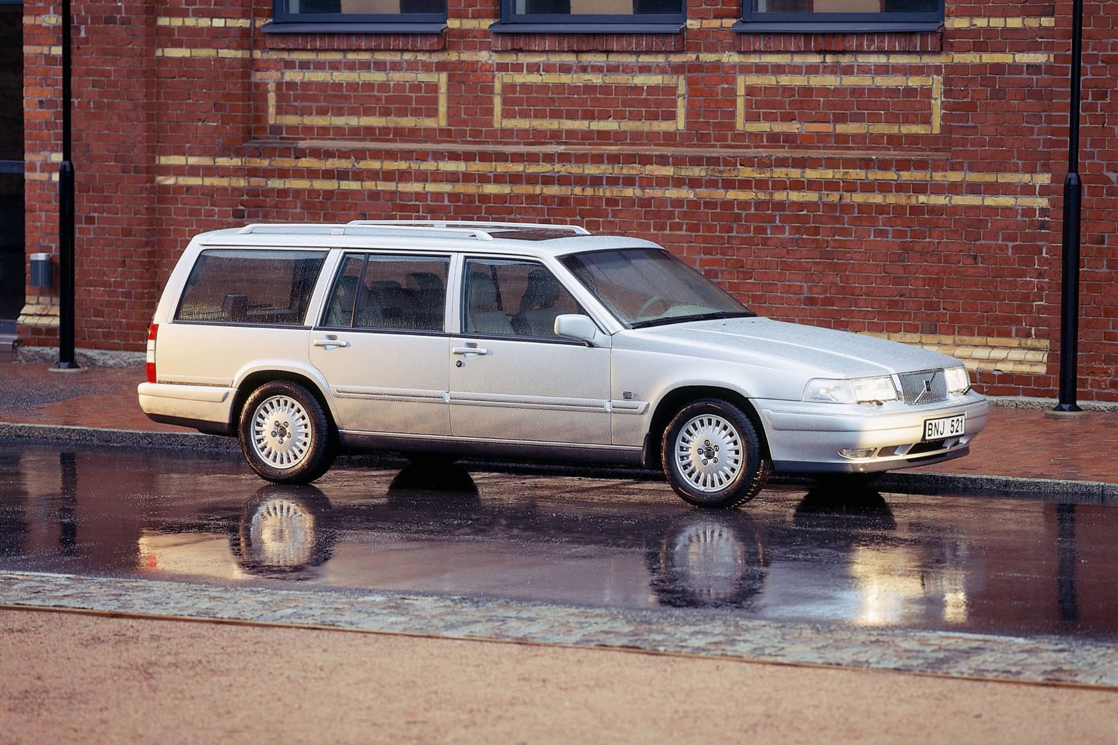 Un Volvo 960/V90 Estate aparcado frente a una casa de ladrillos.
