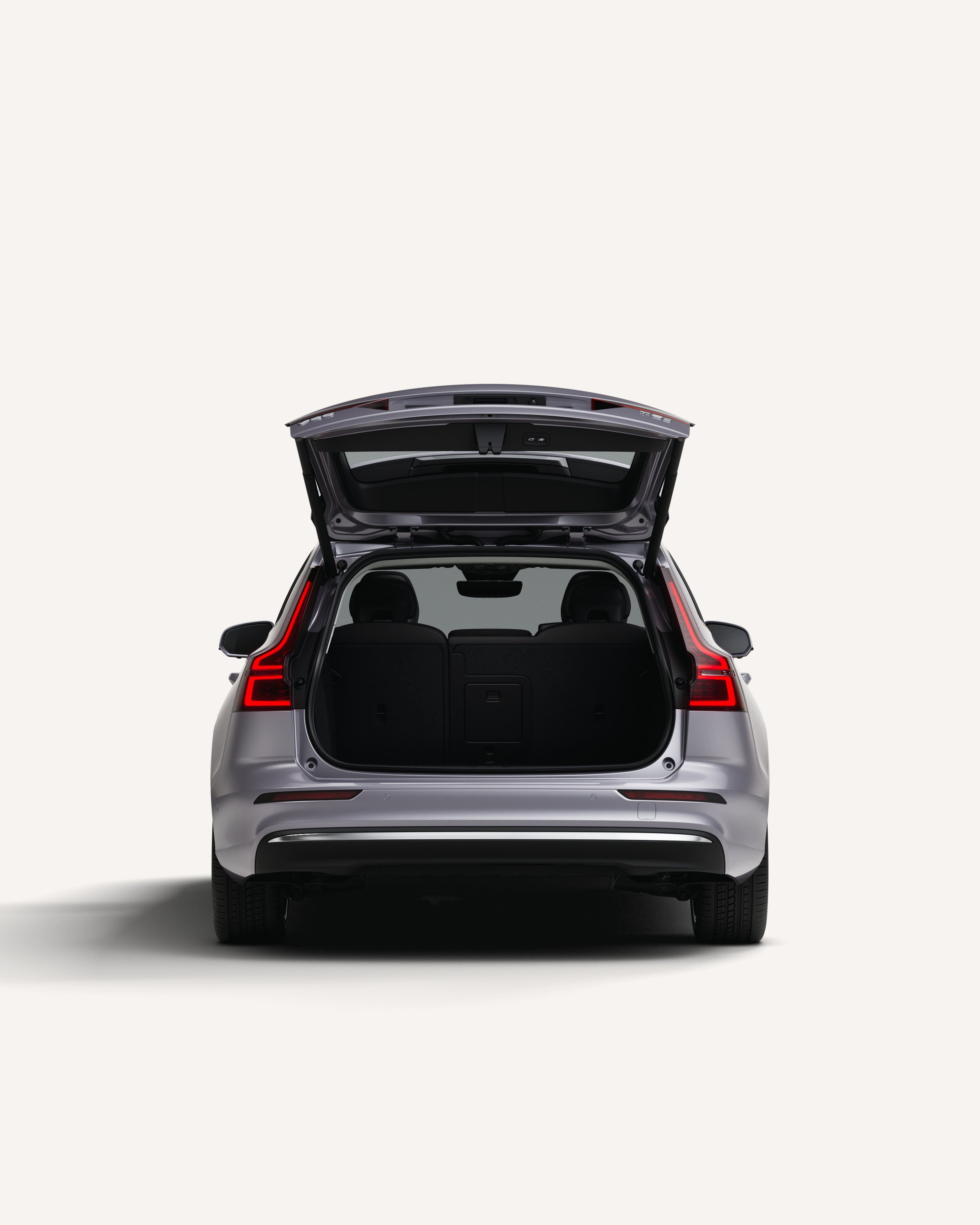 Vue arrière de la Volvo V60 avec le coffre ouvert dans un studio blanc.