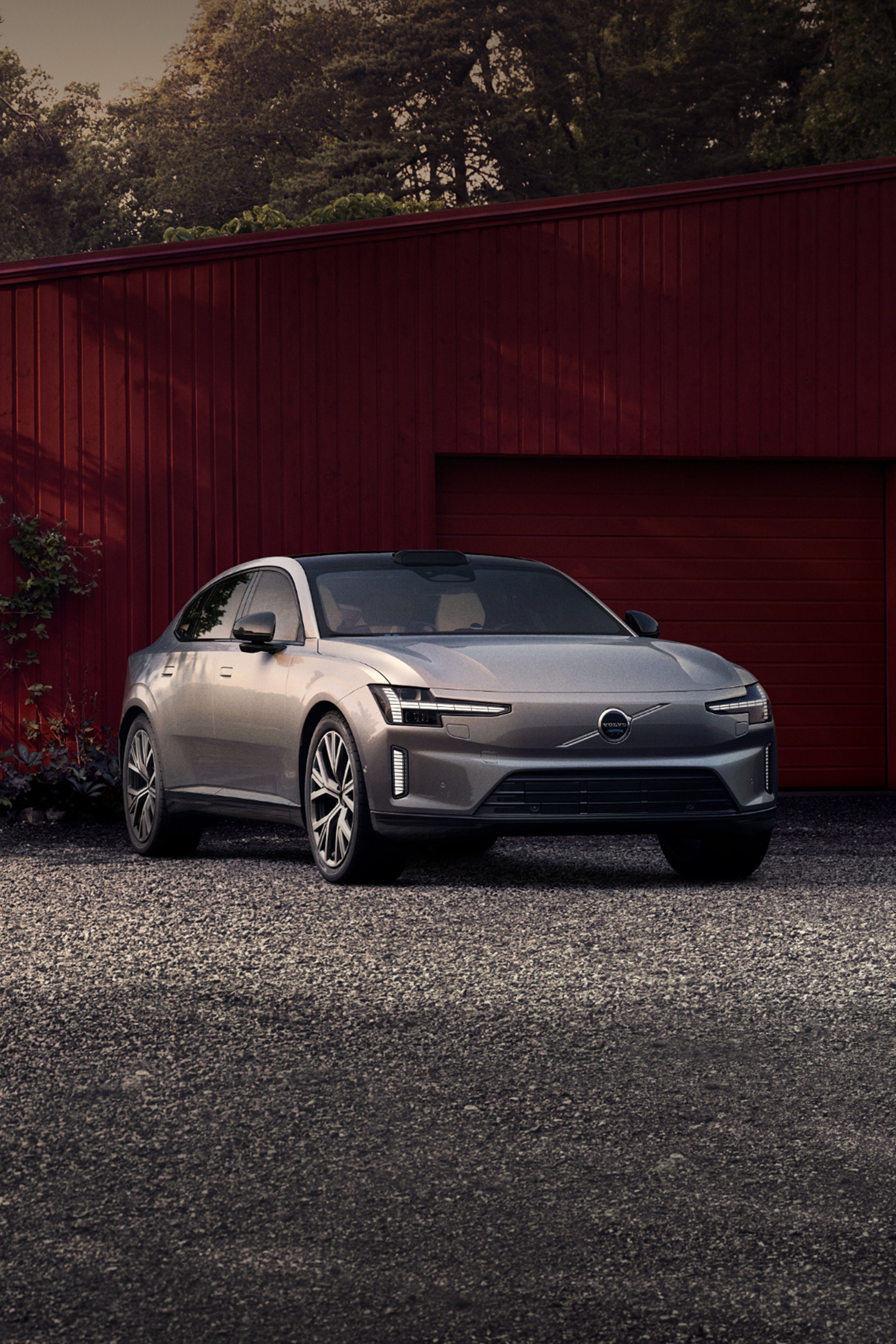 Front view of a silver ES90 parked outside a garage. A man and a boy are greeting a woman next to the garage