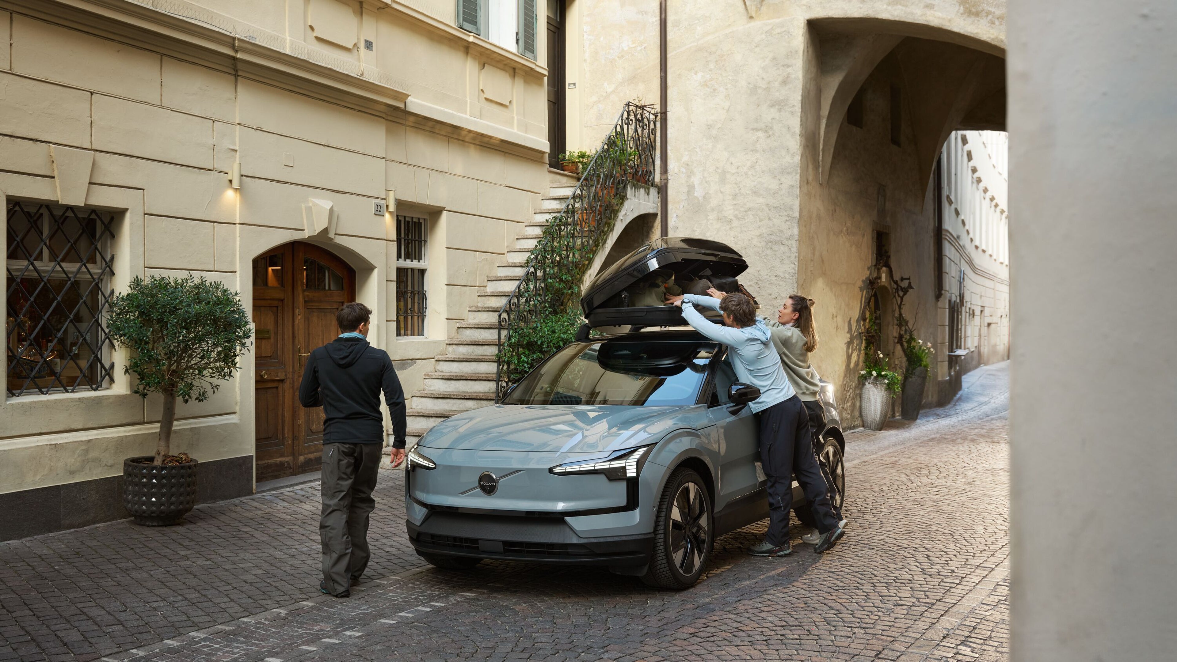 ルーフボックスを装着したEX30に荷物を積み込む3人の友人