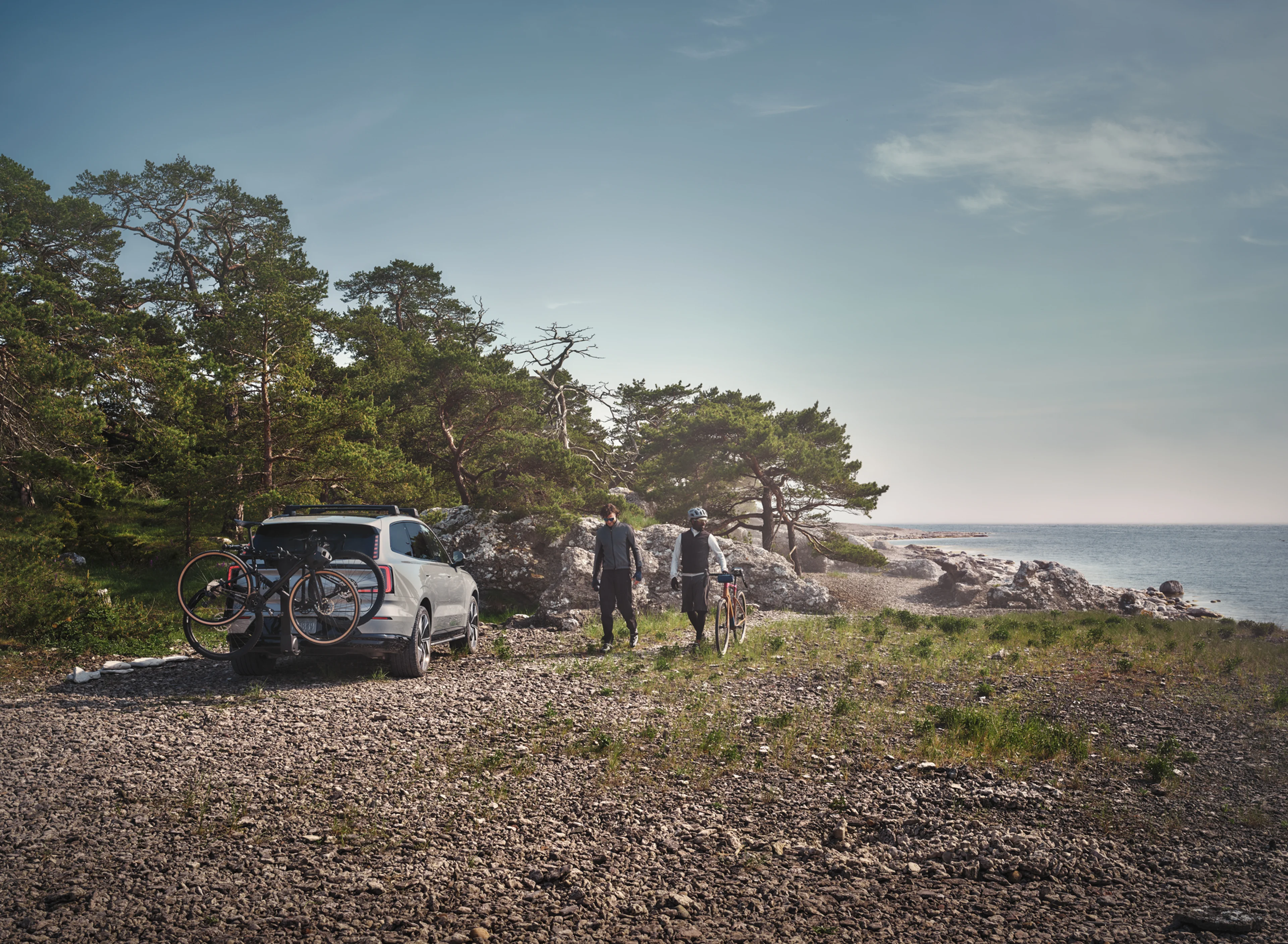 Dva prijatelja vraćaju se u parkirani Volvo s napunjenim nosačima bicikla pričvršćenim za vučnu traku.