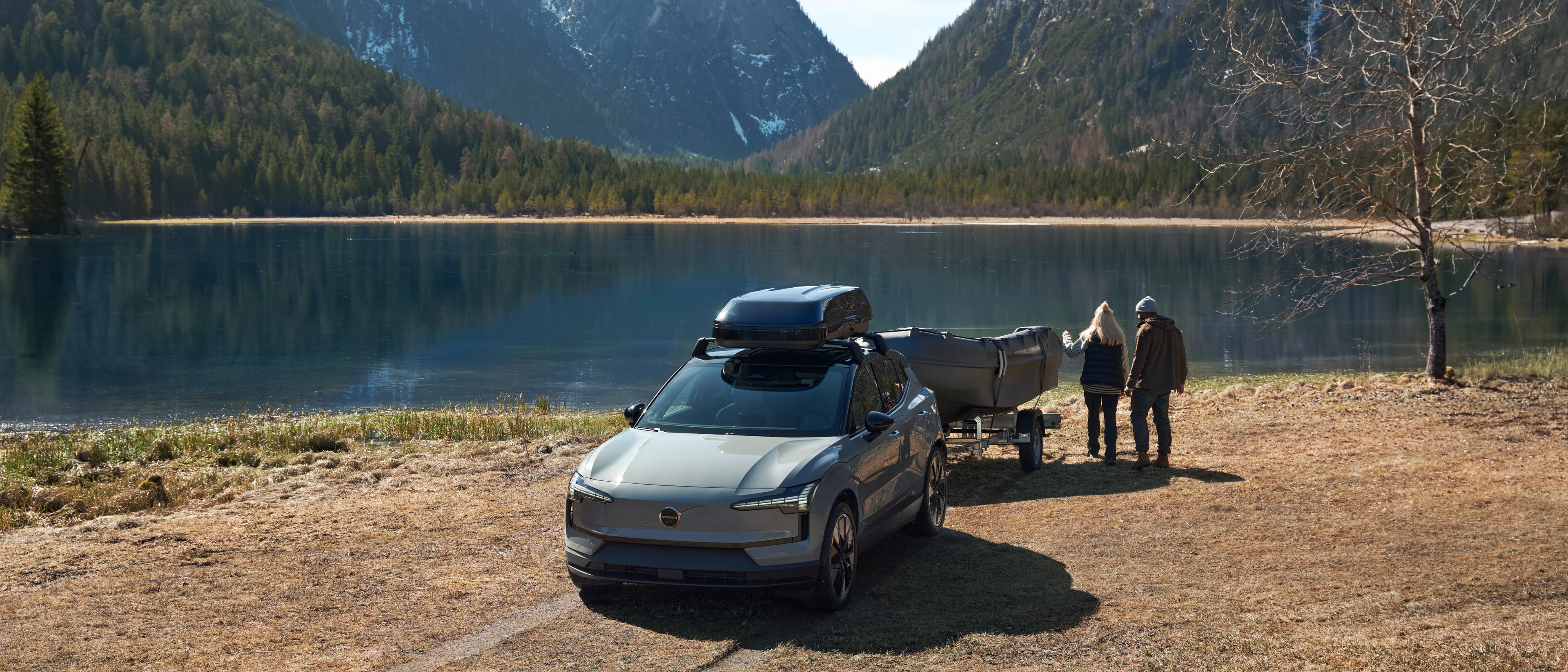 People arriving at a winter lake with a boat attached to their Volvo EX90 using an electric foldable tow bar.