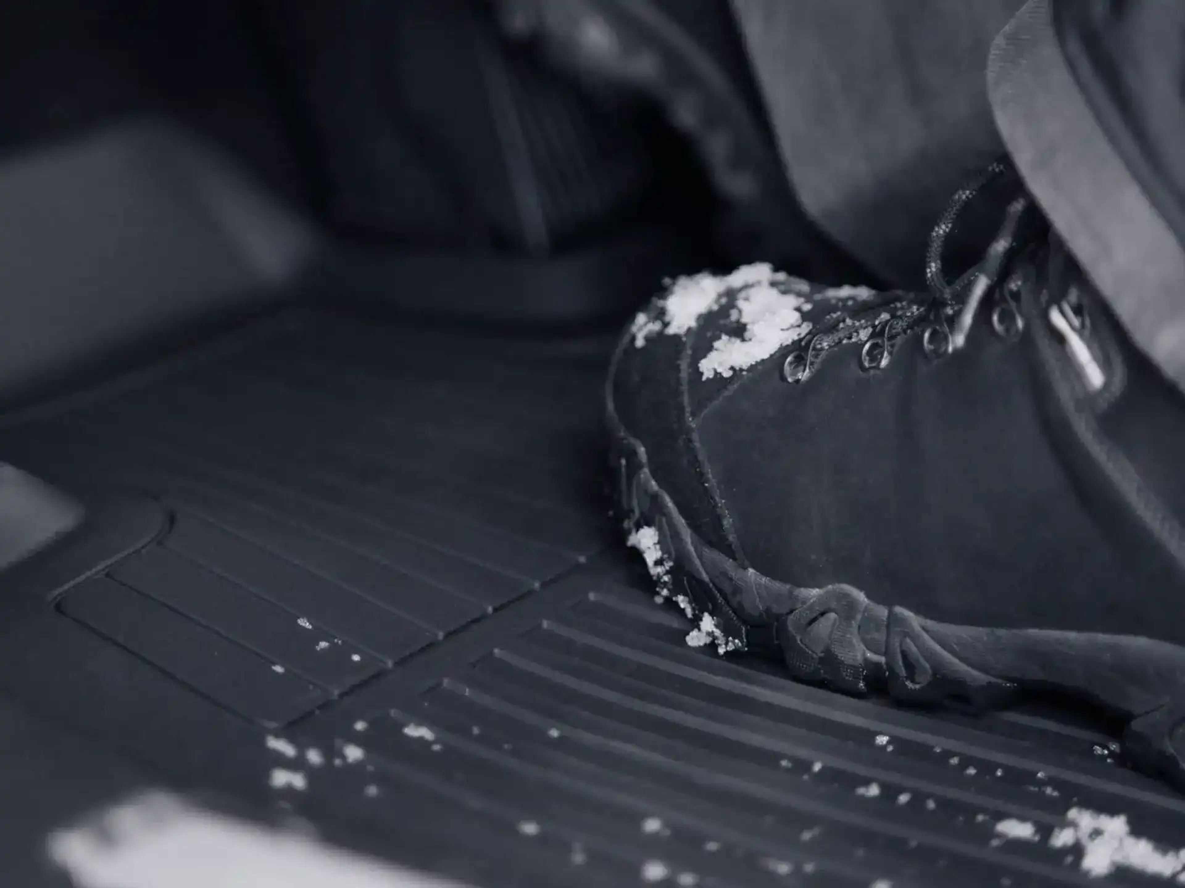 Közeli kép egy hóval borított lábfejről egy Volvo utastérszőnyegen.