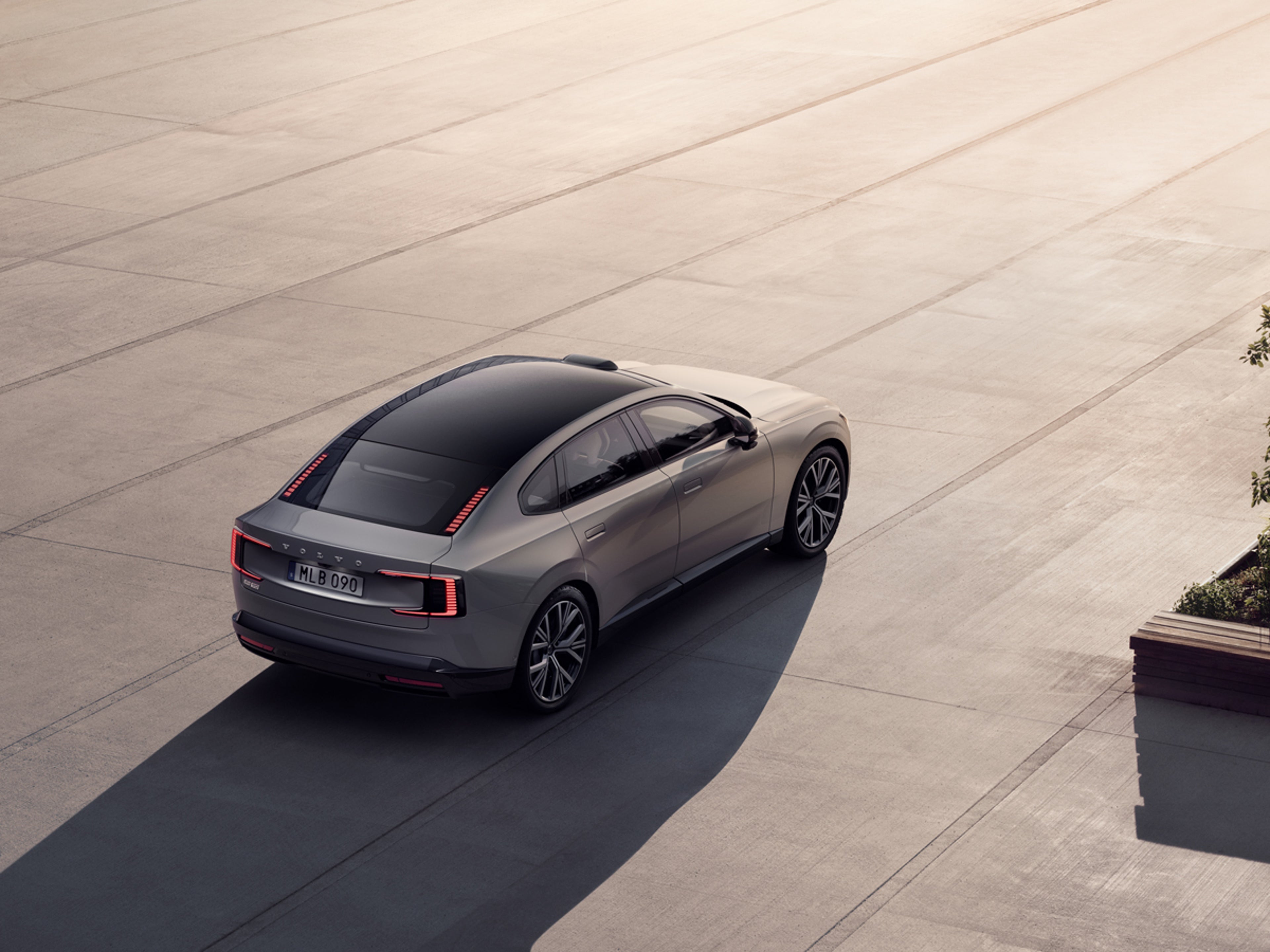 Volvo ES90 på en soldränkt betongplan.