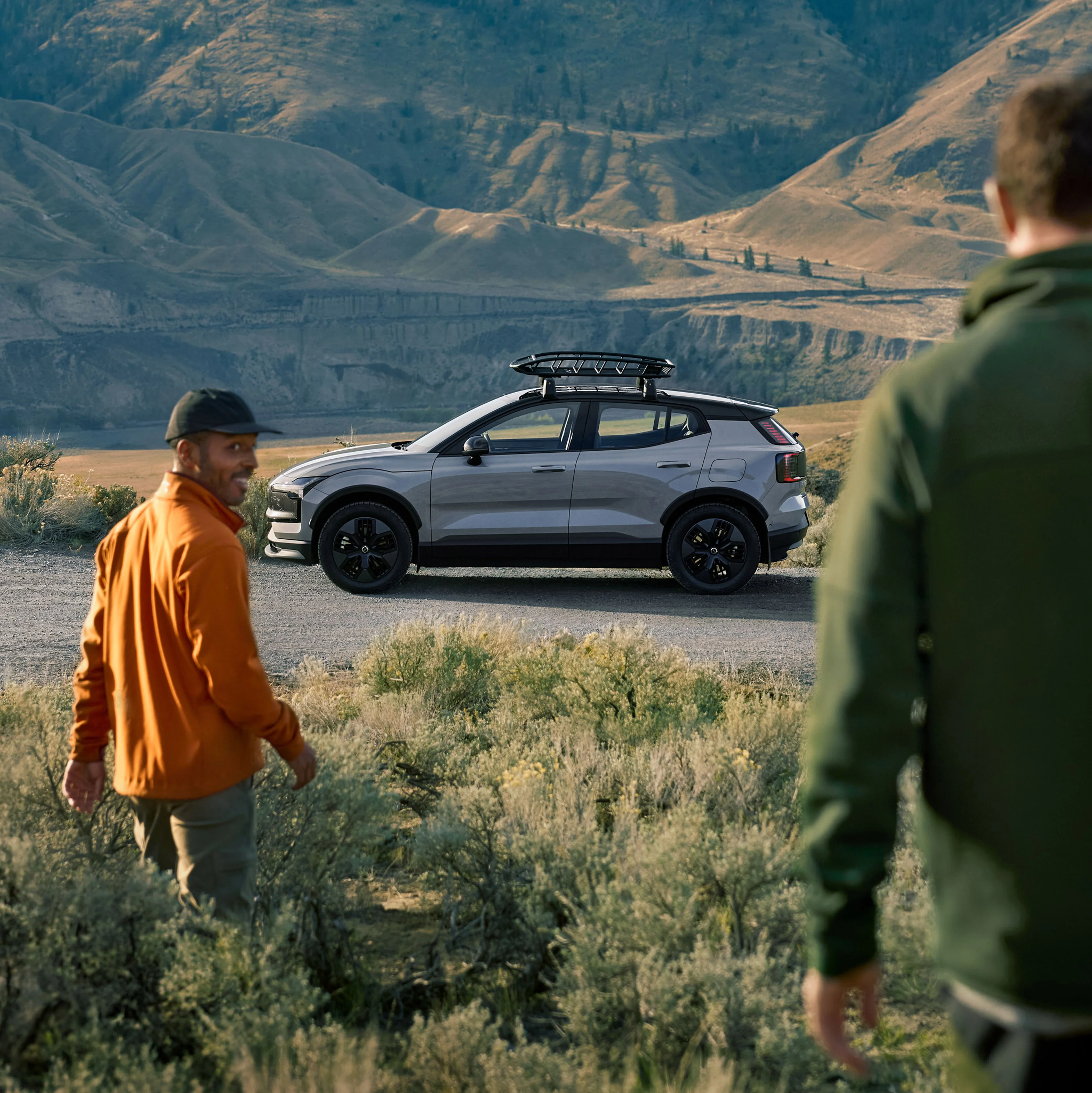 A white Volvo EX30 electric SUV is partially visible, positioned within a modern concrete architectural structure, with sunlight casting shadows on the walls and ground.