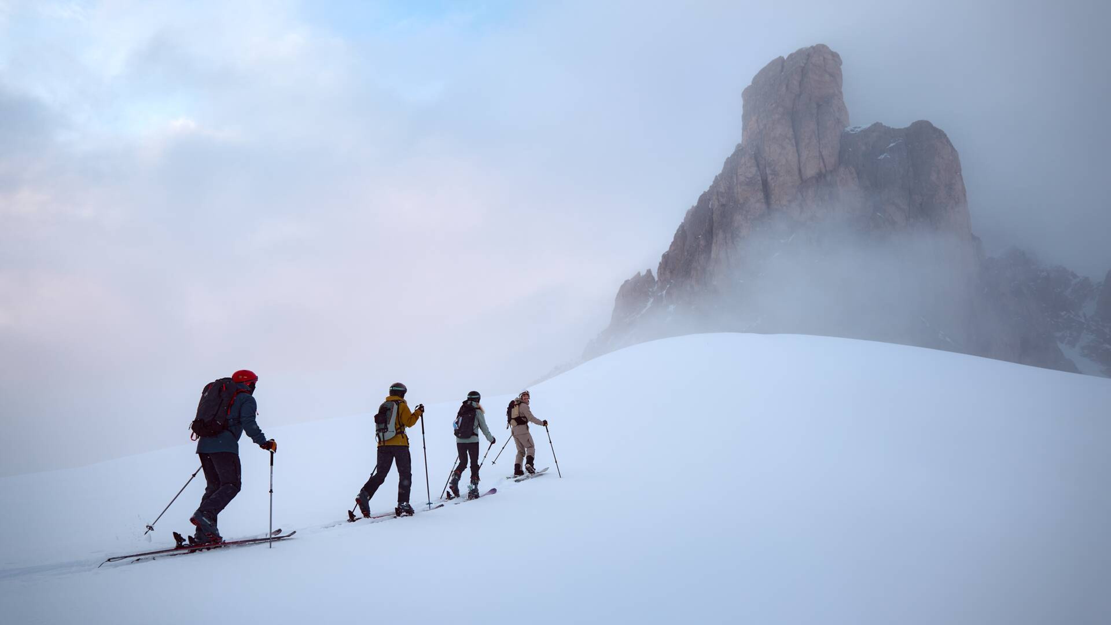 イタリアの山々でバックカントリースキーを楽しむ4人のスキーヤー