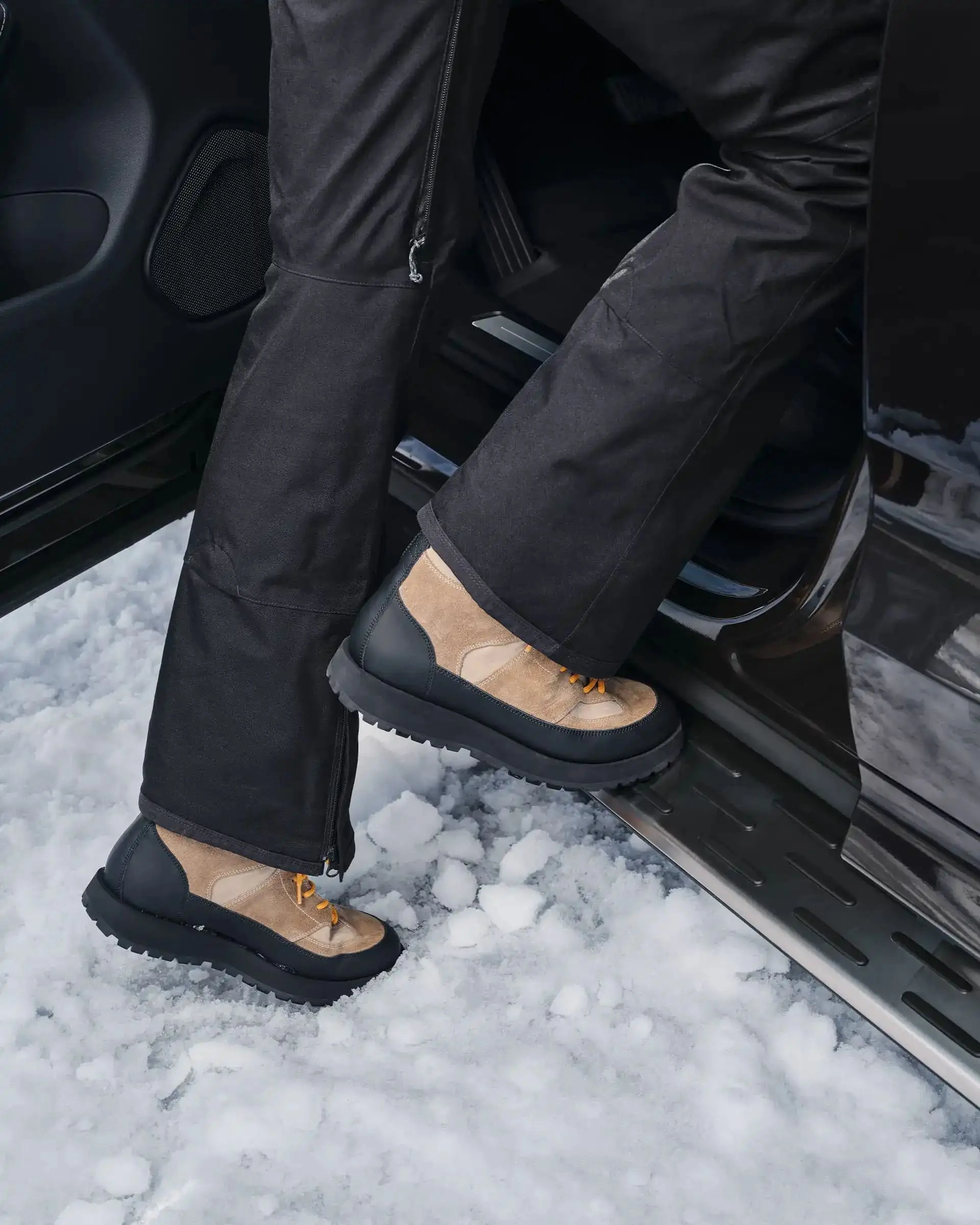 Eine Person in Winterstiefeln steigt auf ein Trittbrett in ein Volvo Fahrzeug.