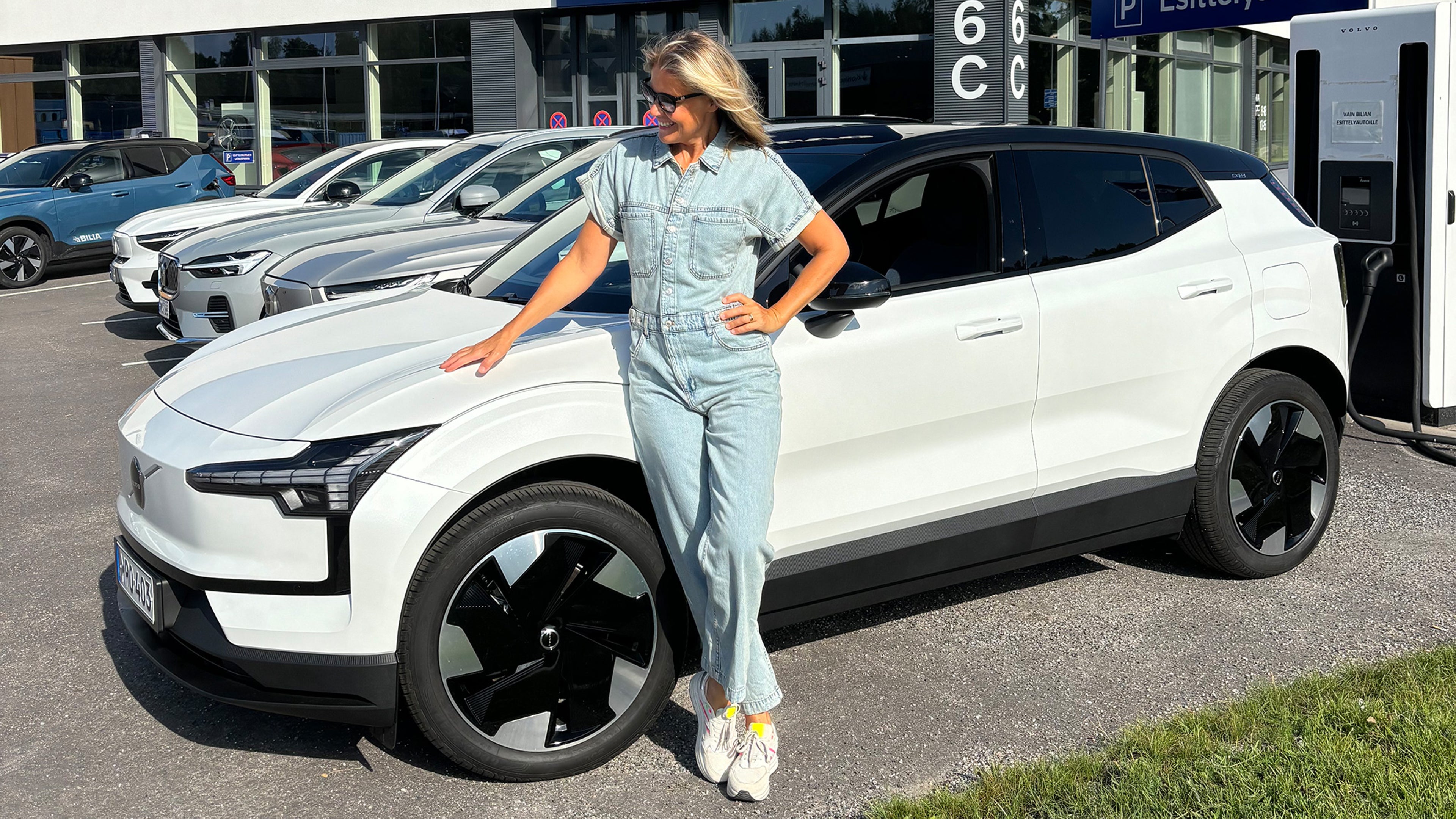 Ella Kanninen nojaa Crystal White -väriseen Volvo EX30 täyssähköautoon Bilia Kaivokselan pihassa.