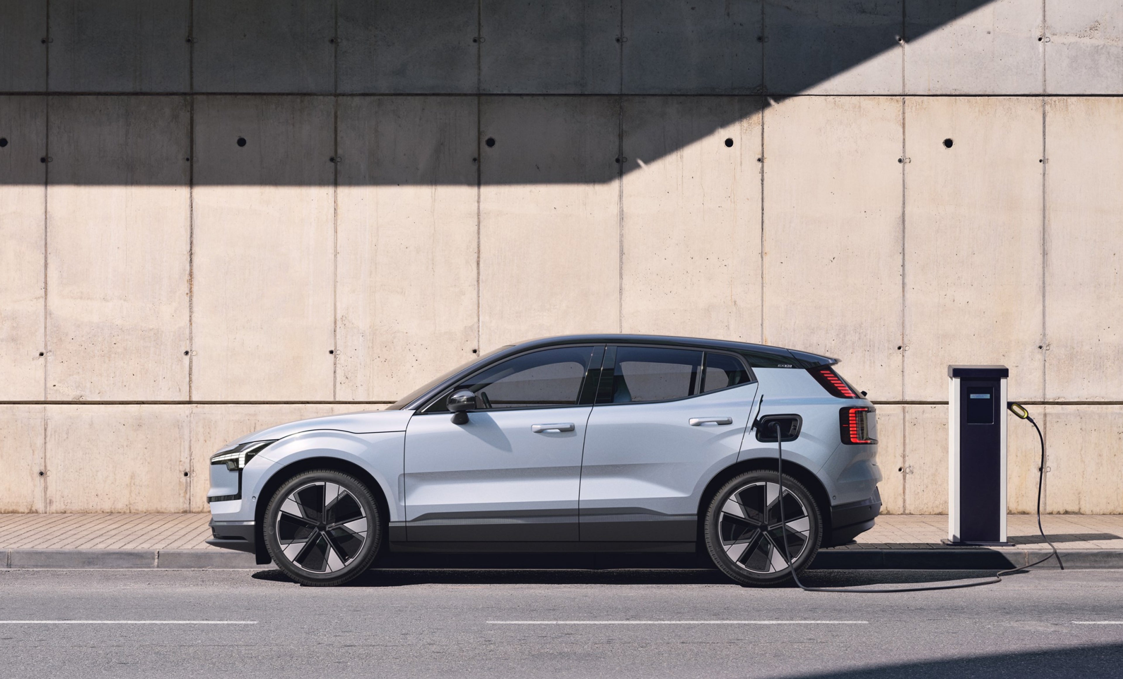 A charging Volvo EX30 parked outside.