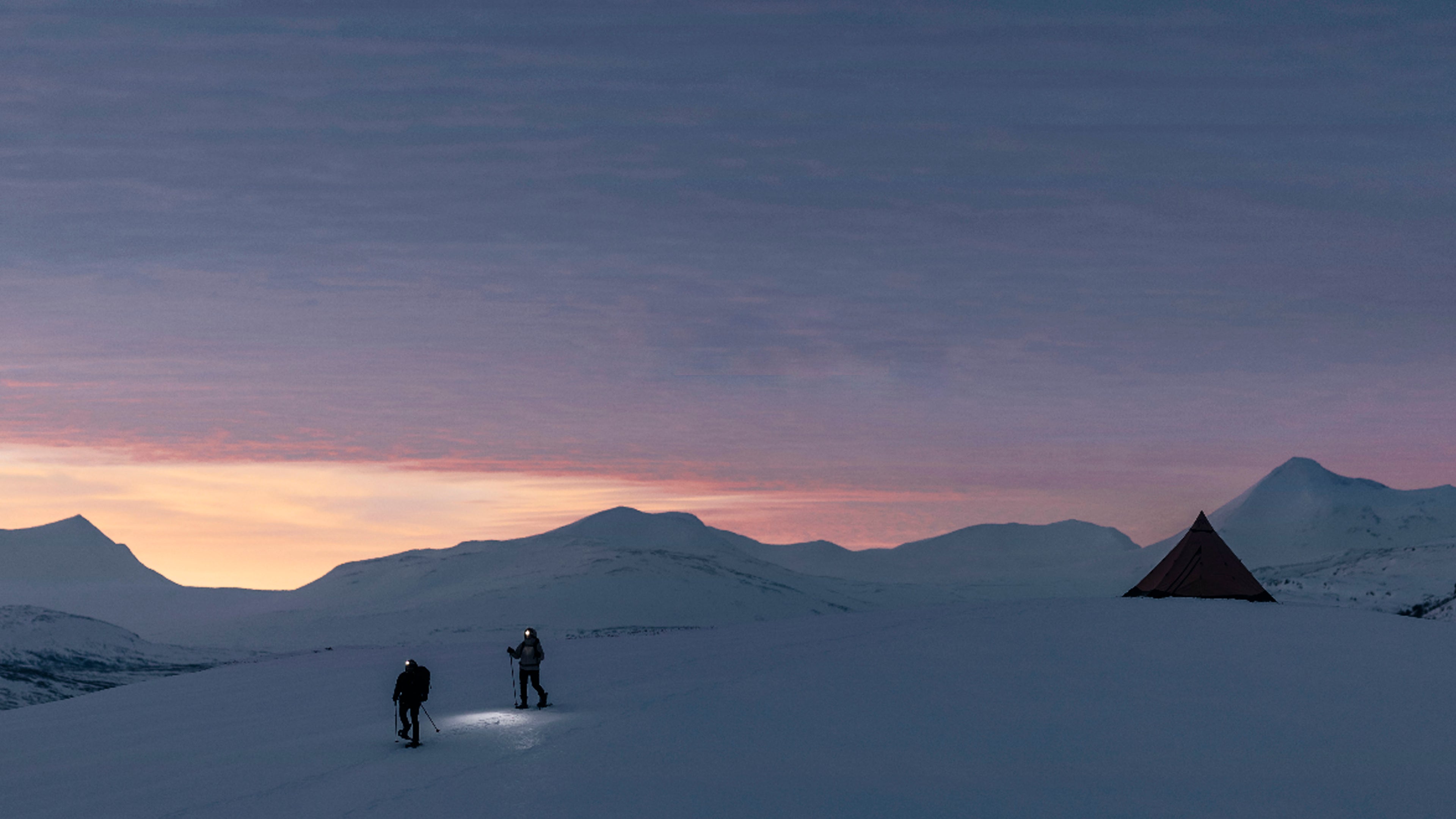 Dos montañistas descendiendo por una ladera nevada entre las montañas