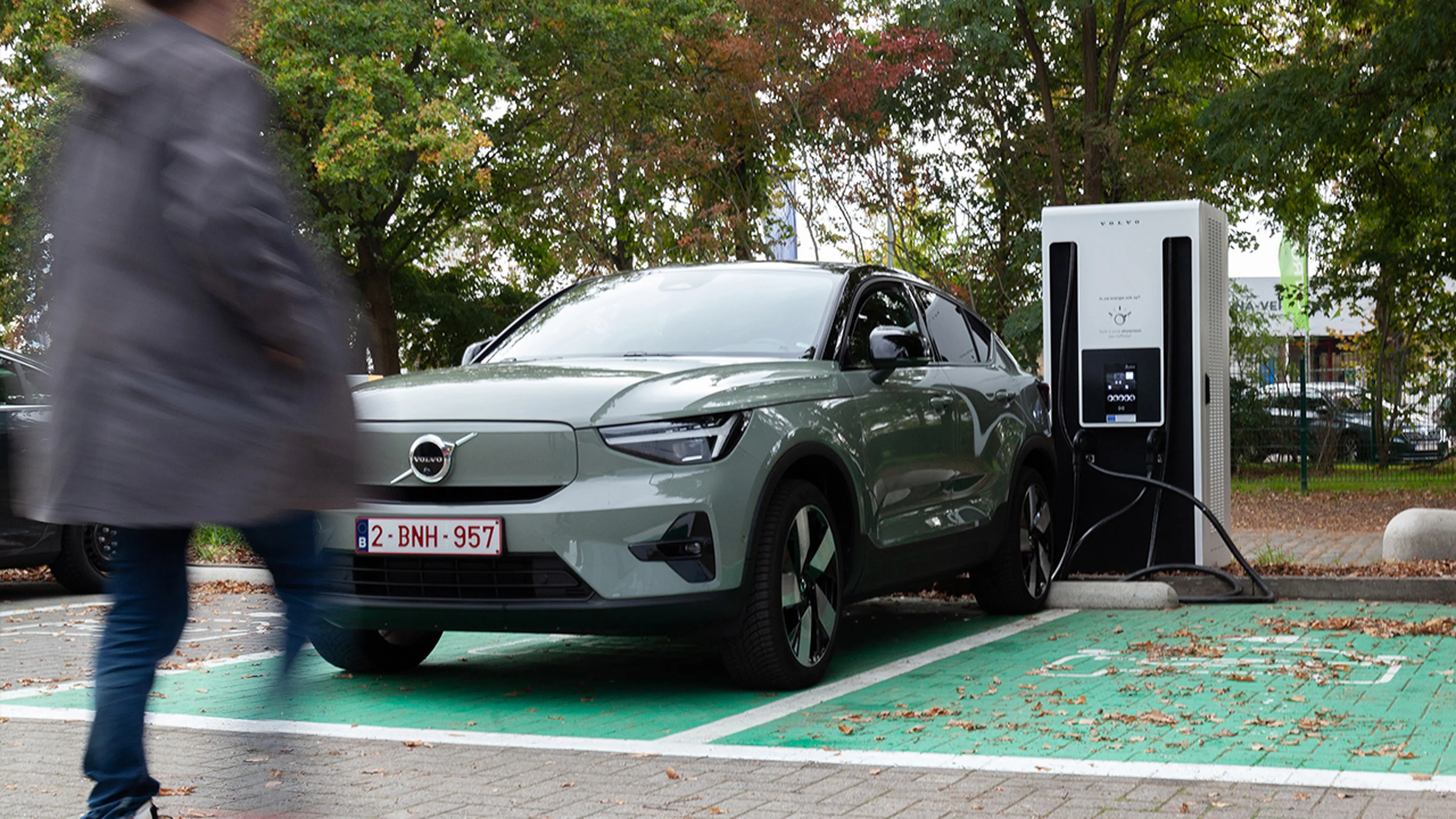 Persoon stapt naar een Volvo XC40 Recharge die oplaadt aan een Powerstop laadpaal.