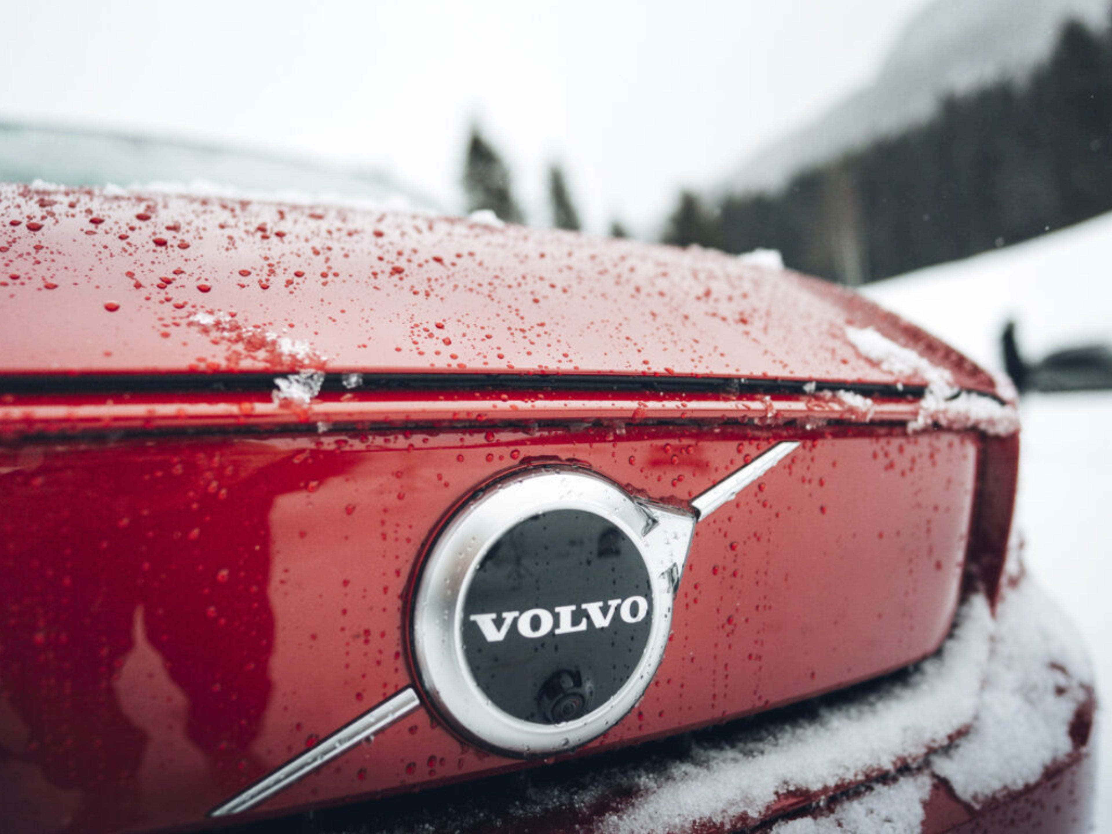 Nahaufnahme des Volvo Logos auf einem roten Volvo EX40.