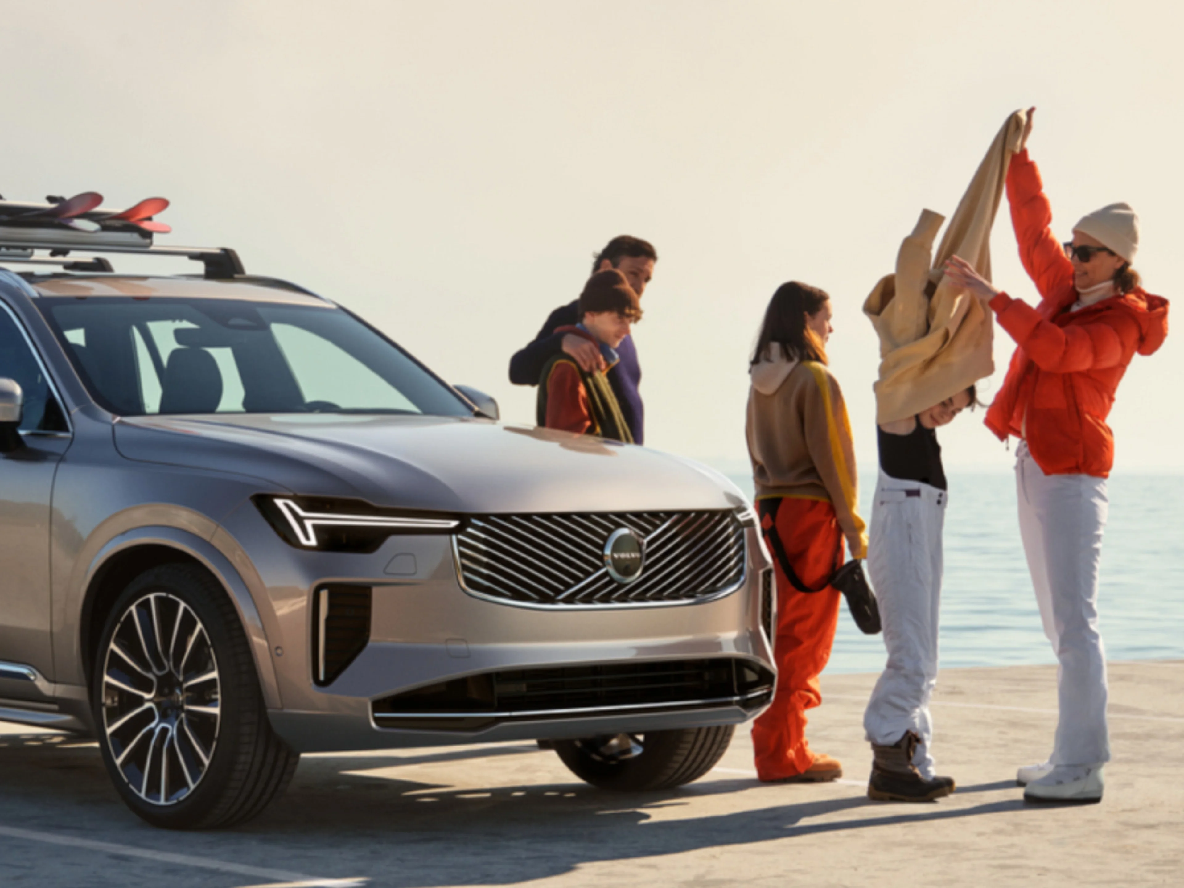 Aufnahme einer Familie, die sich um einen Volvo EX90 versammelt hat, der gerade umgezogen wird.