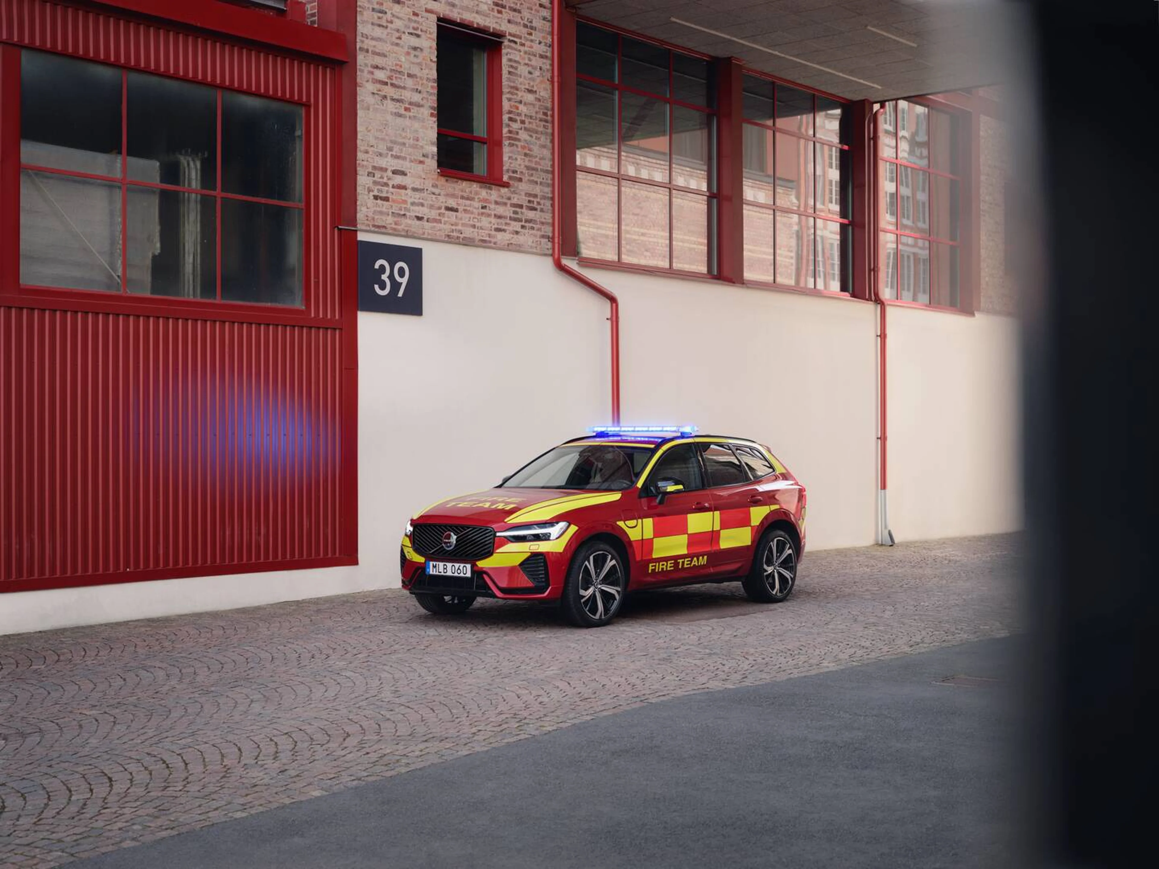 Un automóvil de emergencia rojo del equipo de bomberos Volvo XC60 estacionado fuera de una estación de bomberos.