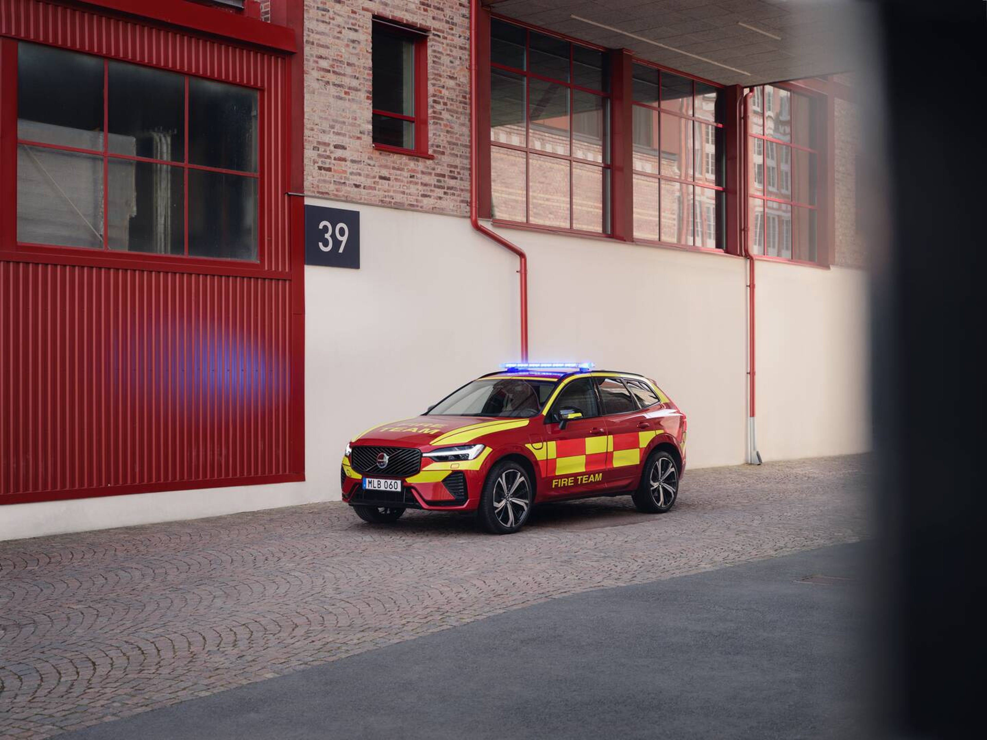 Црвено возило за итни случаи на противпожарната екипа Volvo XC60 паркирано пред противпожарна станица.