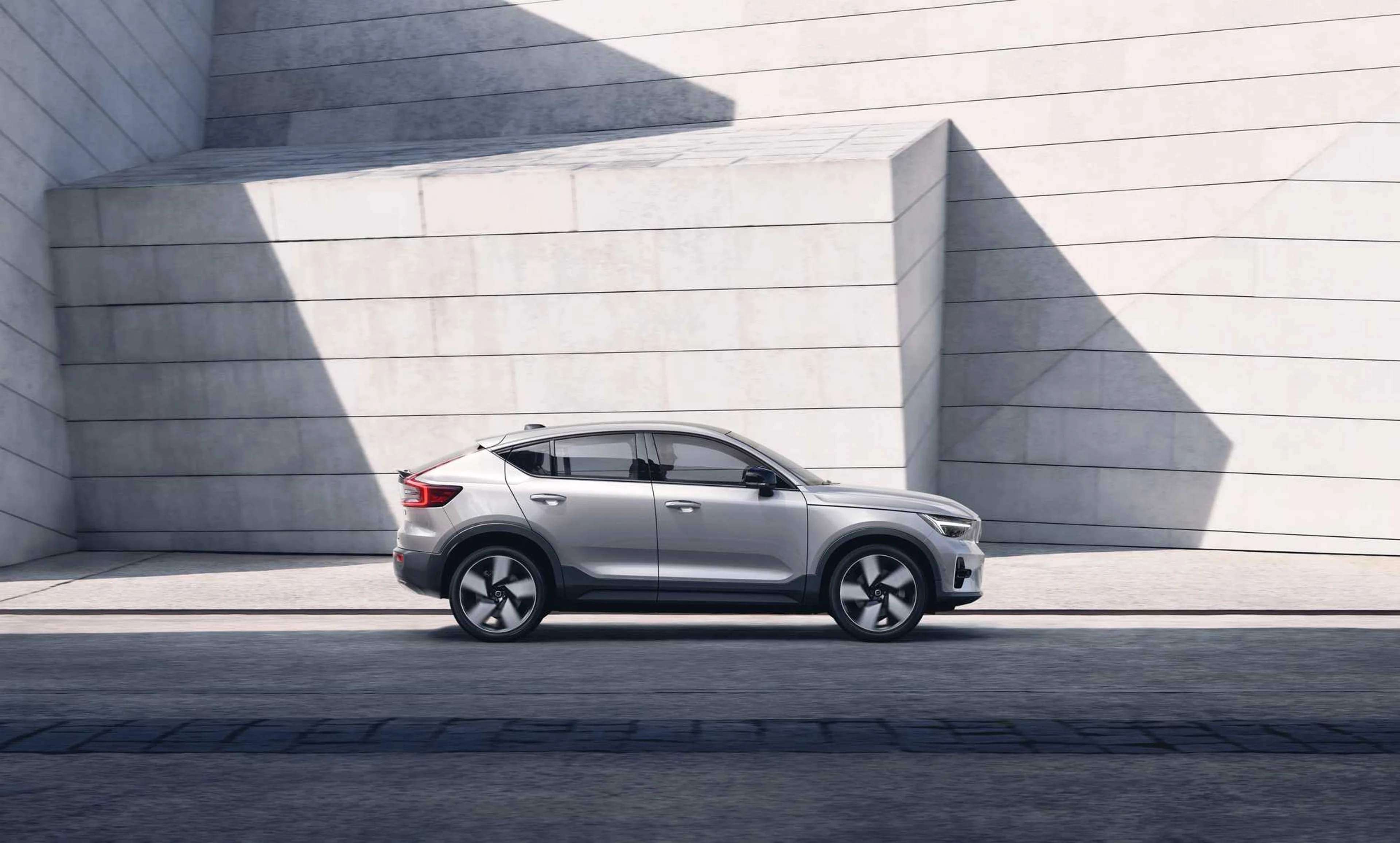 A silver Volvo C40 driving down road.