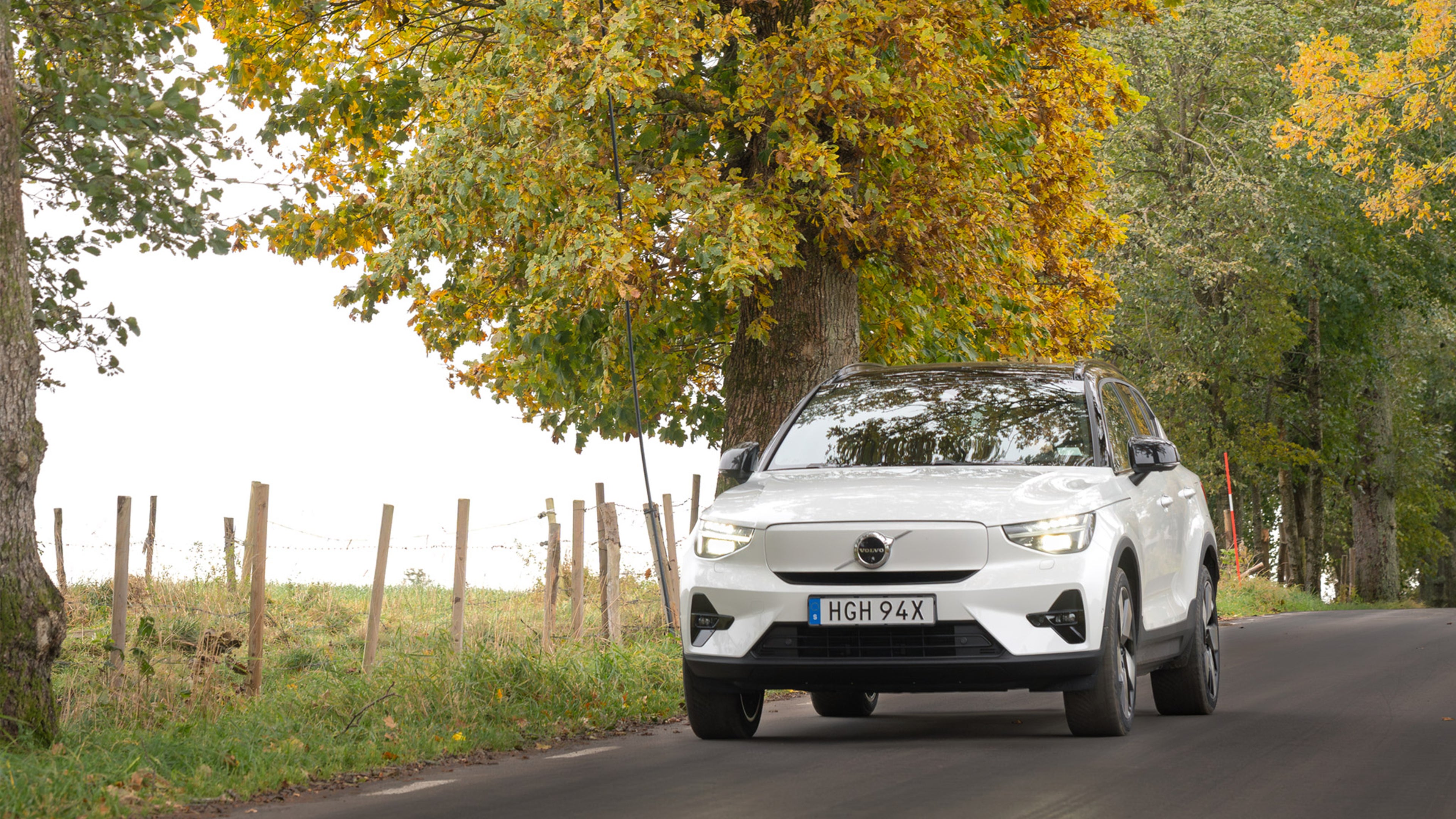 Valkoinen Volvo EX40 täyssähköauto ajaa syksyisessä maisemassa.