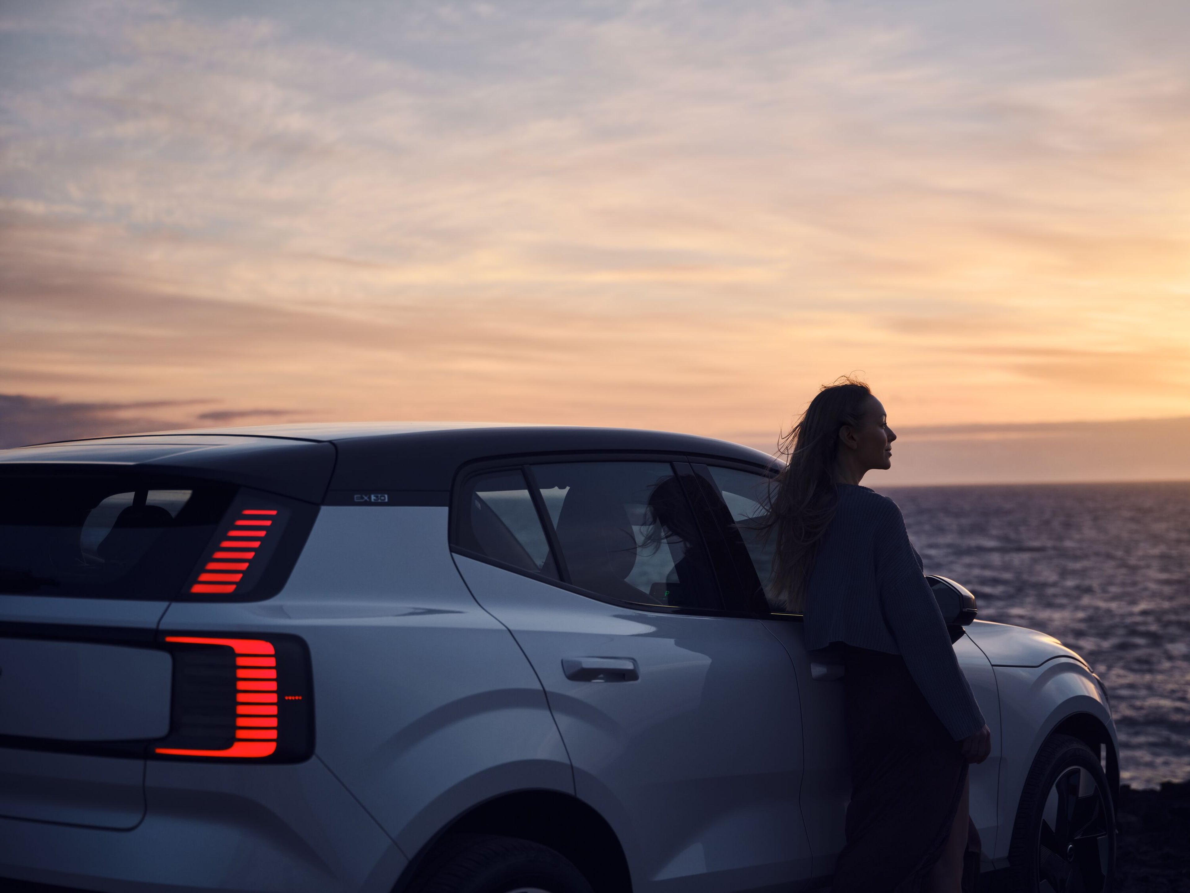 obrázok kampane Ocean Race 2025, na ktorom žena stojí pri oceáne vedľa auta