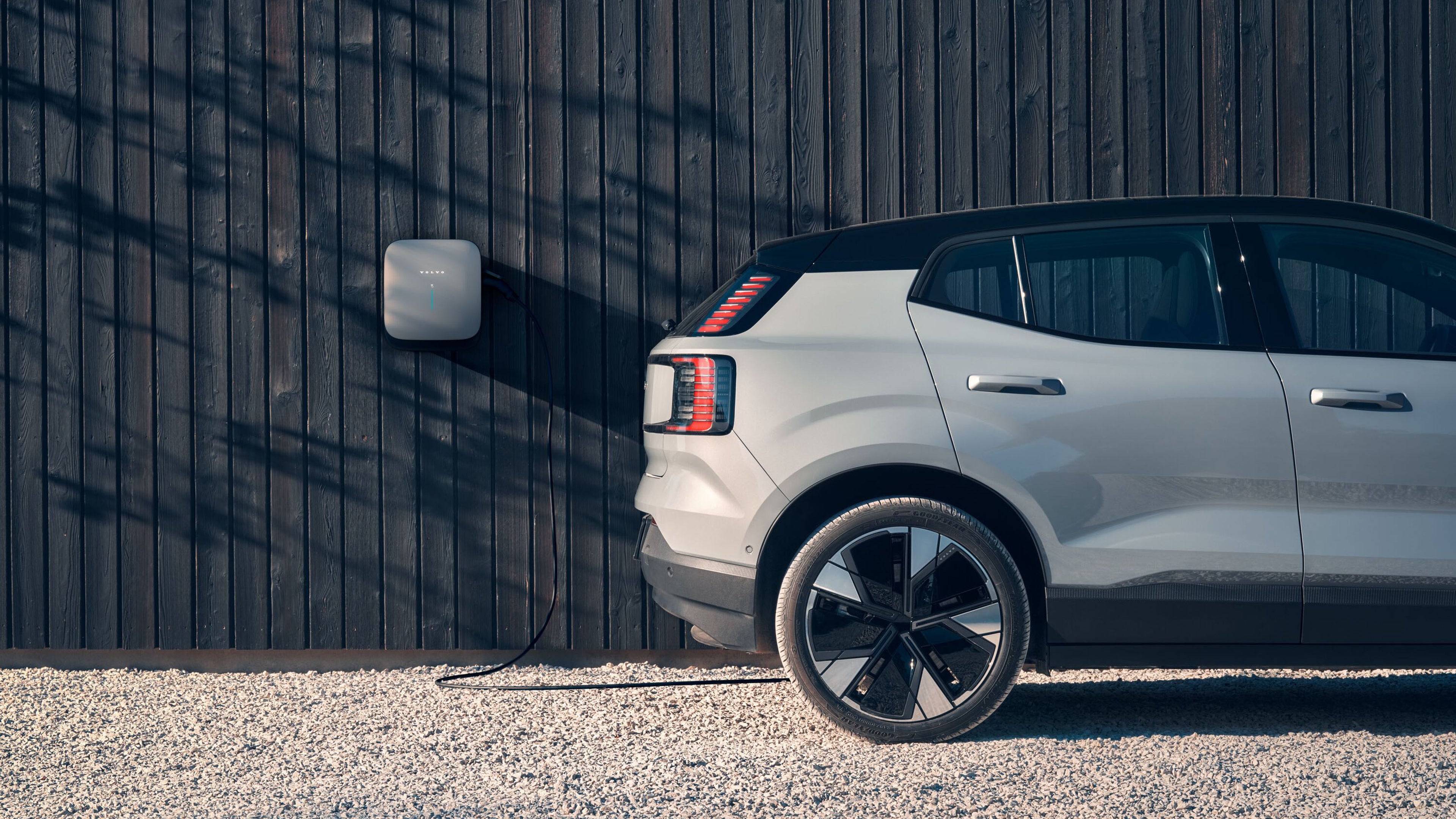 Volvo EX30 zaparkované pri stene a pripojené na nástennú nabíjačku wallbox Volvo
