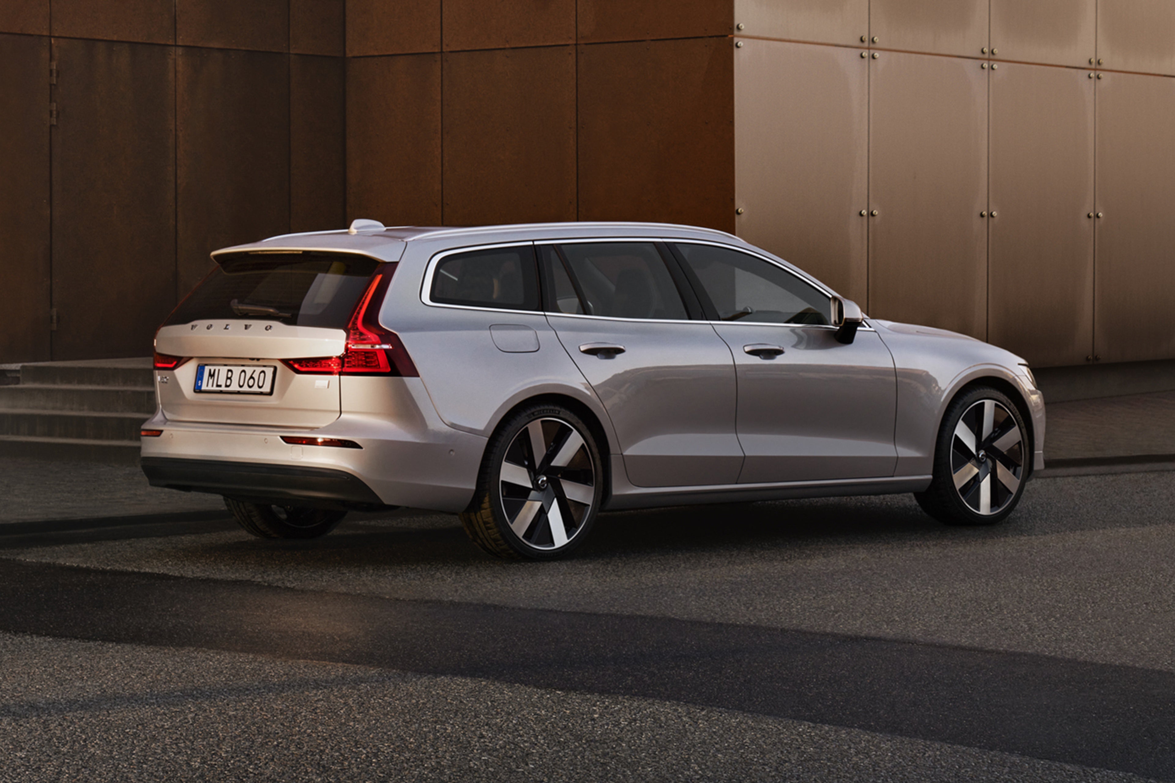 Silver Dawn -värinen Volvo V60 lataushybridiauto pysäköitynä seinän viereen.