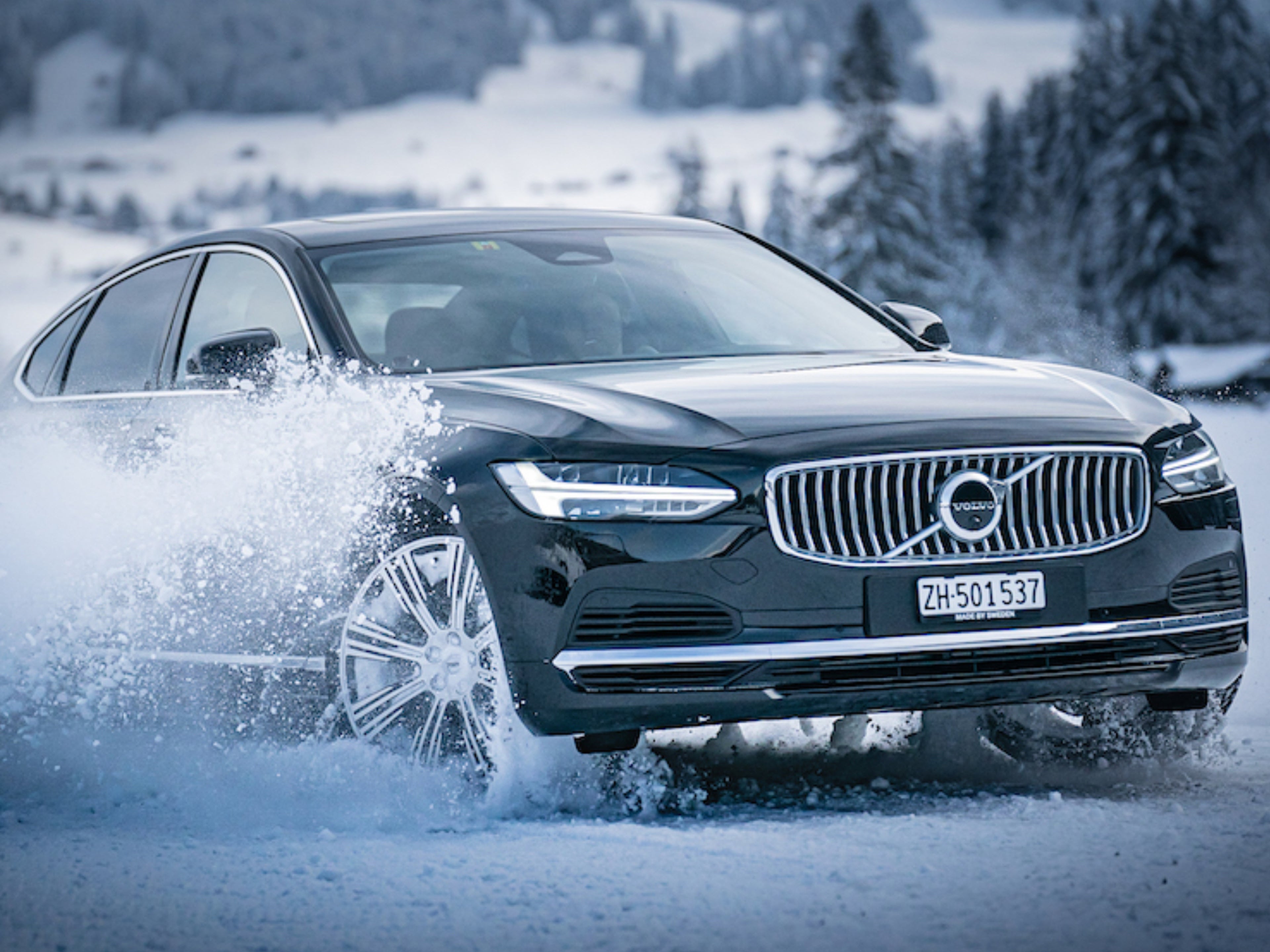 Ripresa frontale di una Volvo V90 nera durante un giro di prova sulla neve.