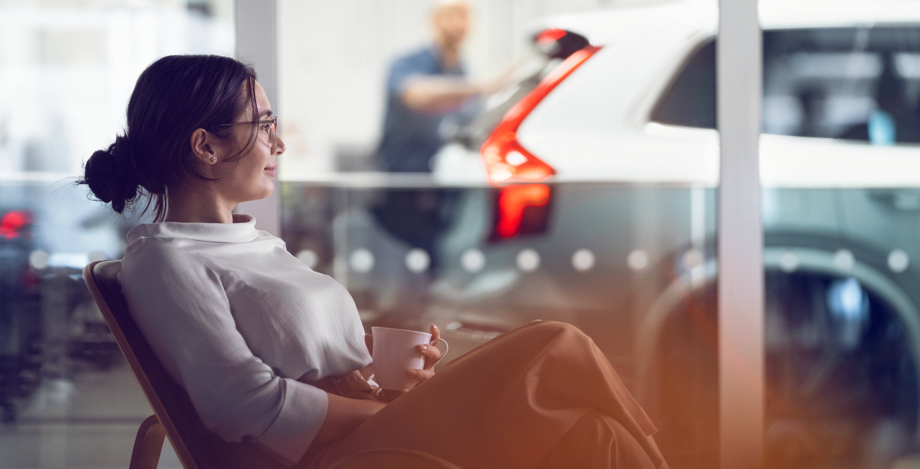 Nainen istuu kahvilla ja odottaa huollon valmistusta Volvo huollossa.