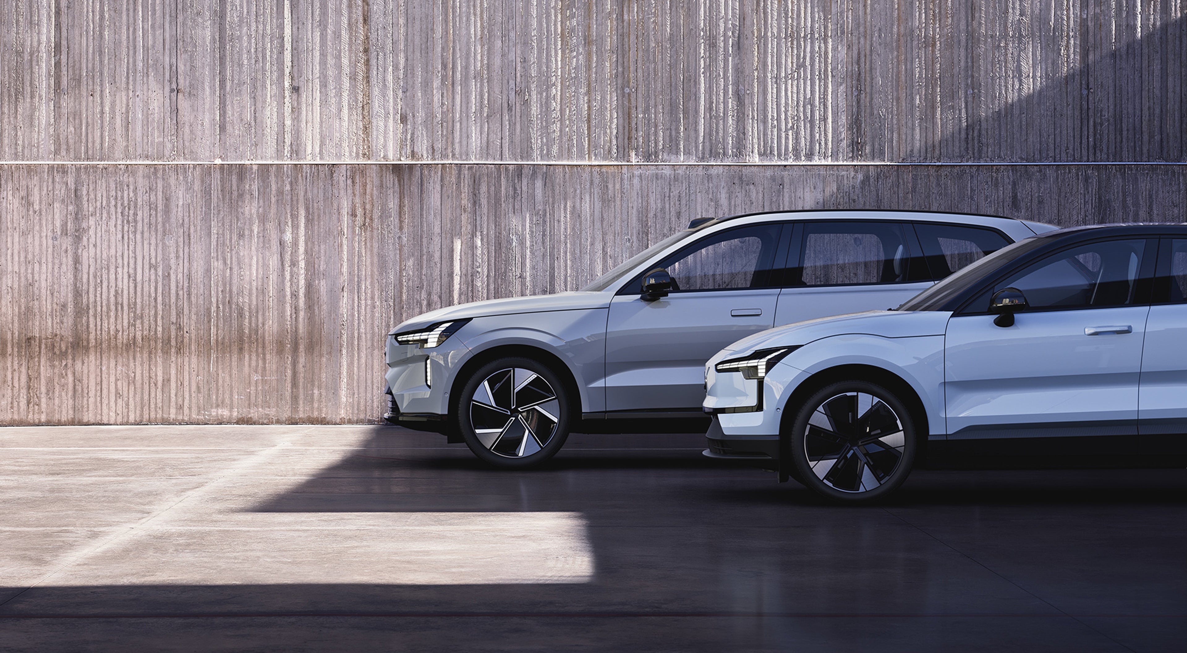 Fleet of pure electric Volvo cars standing by a concrete wall.