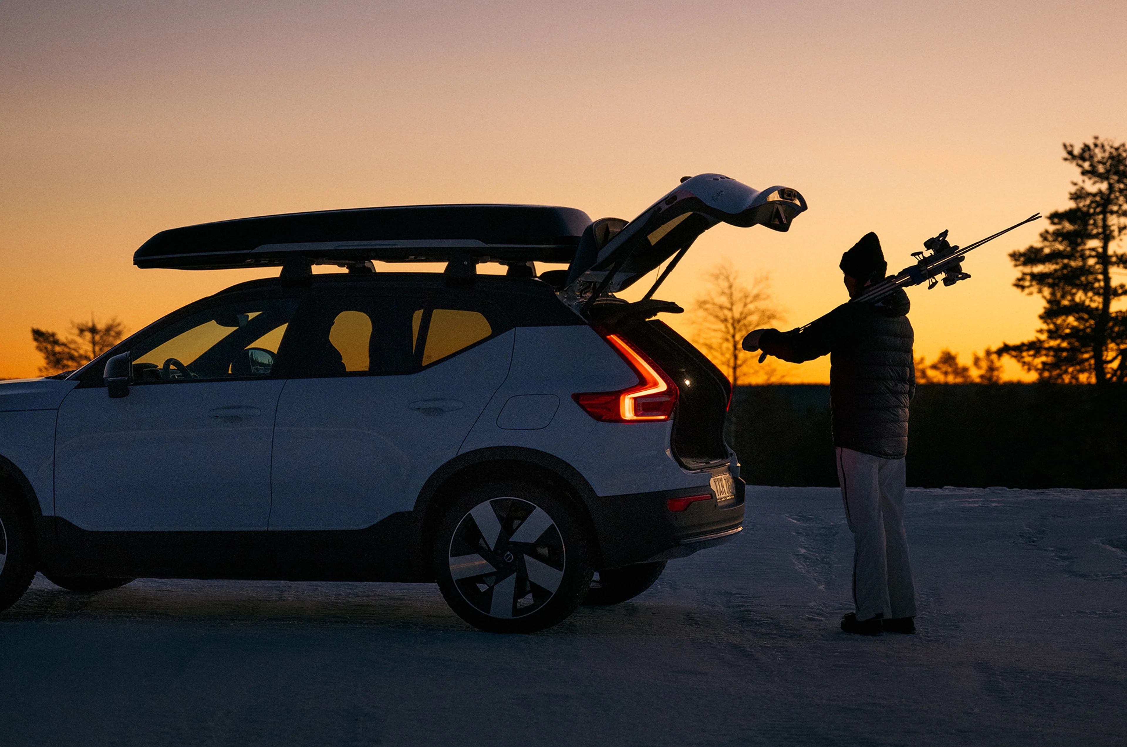 Volvo EX40 parkol hóval borított földön, naplementekor