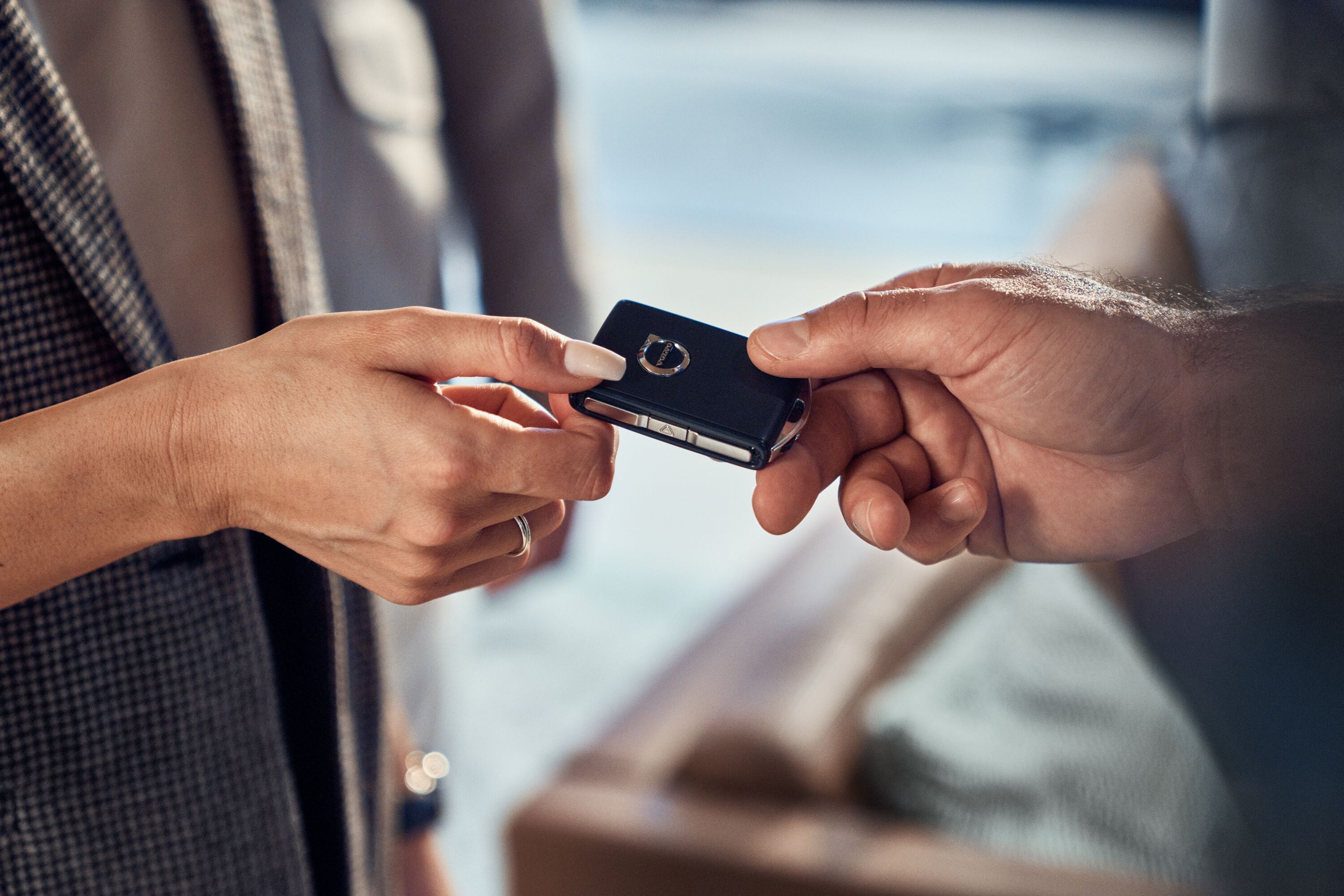 Two hands exchanging a Volvo car key fob ahead of a test drive for company car drivers.